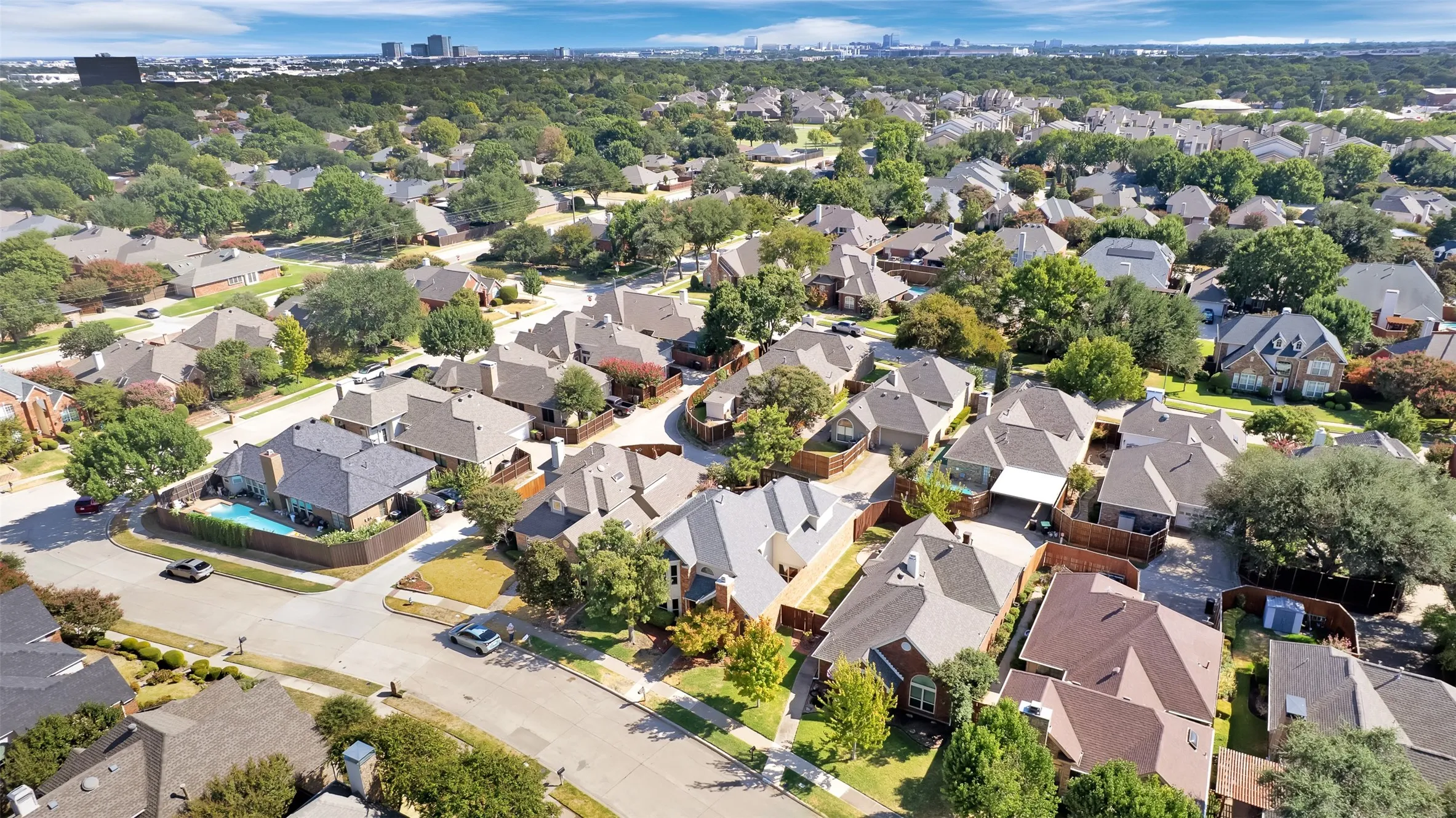 Densely developed residential area featuring mature trees and a distant city skyline