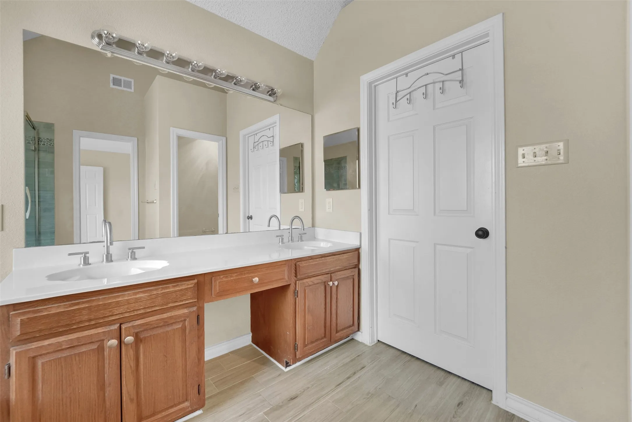Dual vanity with under-mount sinks, wood-finish cabinetry, and a spacious counter
