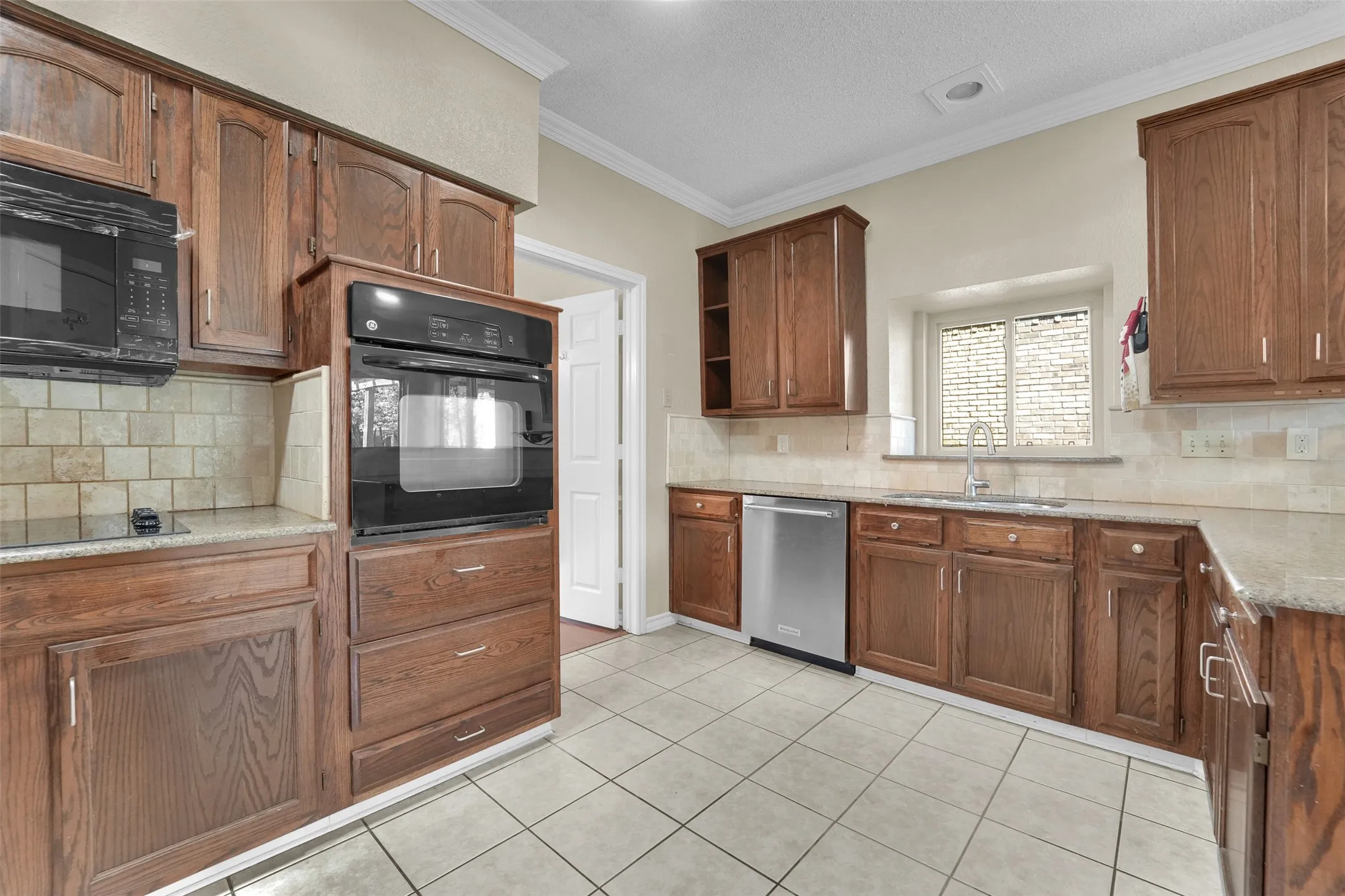 Kitchen featuring wood cabinetry, light-toned tile flooring, light-toned countertops, and a built-in oven