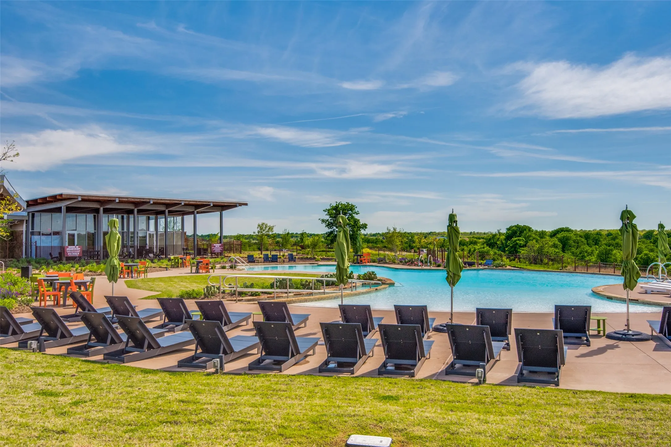 Expansive outdoor pool deck featuring a large swimming pool, surrounding lounge areas, and an adjacent covered structure with floor-to-ceiling windows