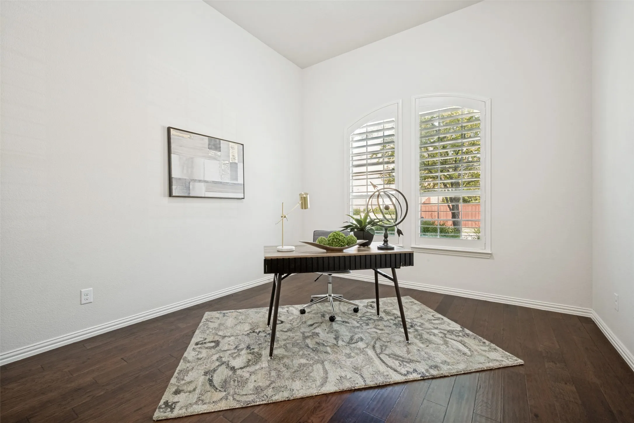 Arched windows with plantation shutters, vaulted ceiling, and dark wood-finish flooring