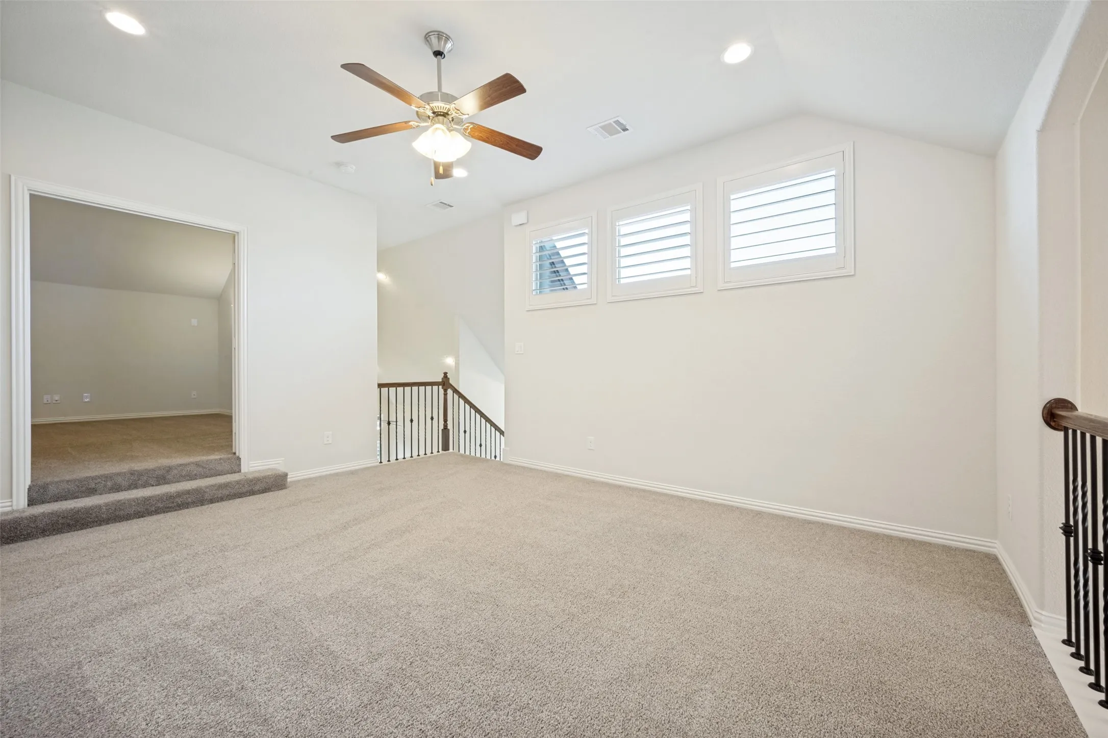 Carpeted room featuring a ceiling fan, recessed lighting, and three shuttered windows