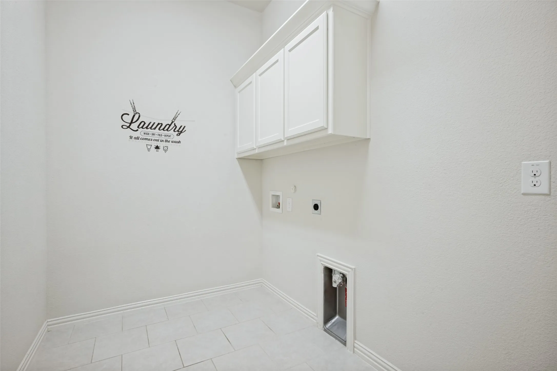Utility space featuring white cabinetry, light-toned floor tiling, and a dedicated laundry hookup