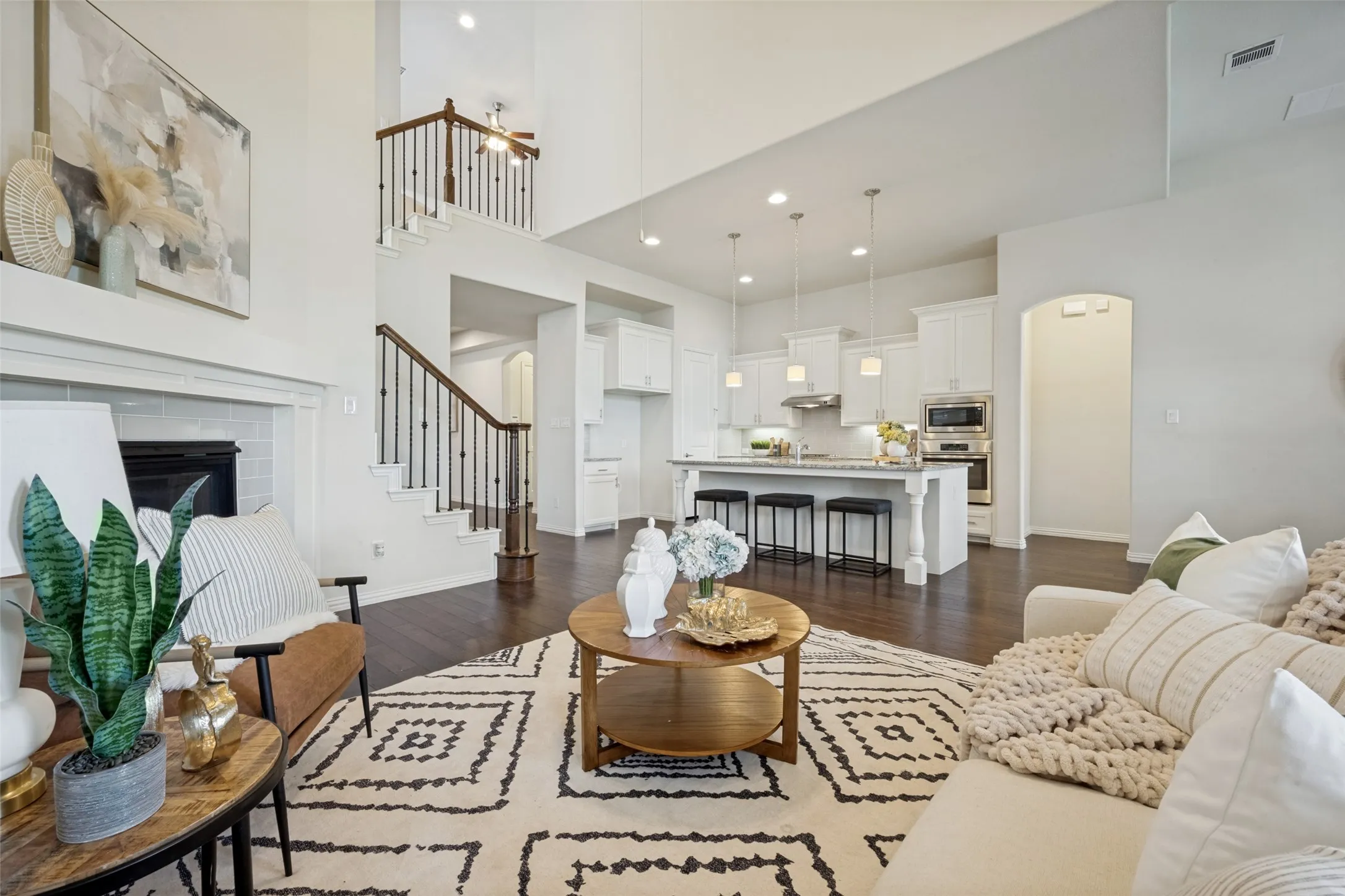 Vaulted ceilings, a built-in fireplace with a white mantel, and wood-finish flooring