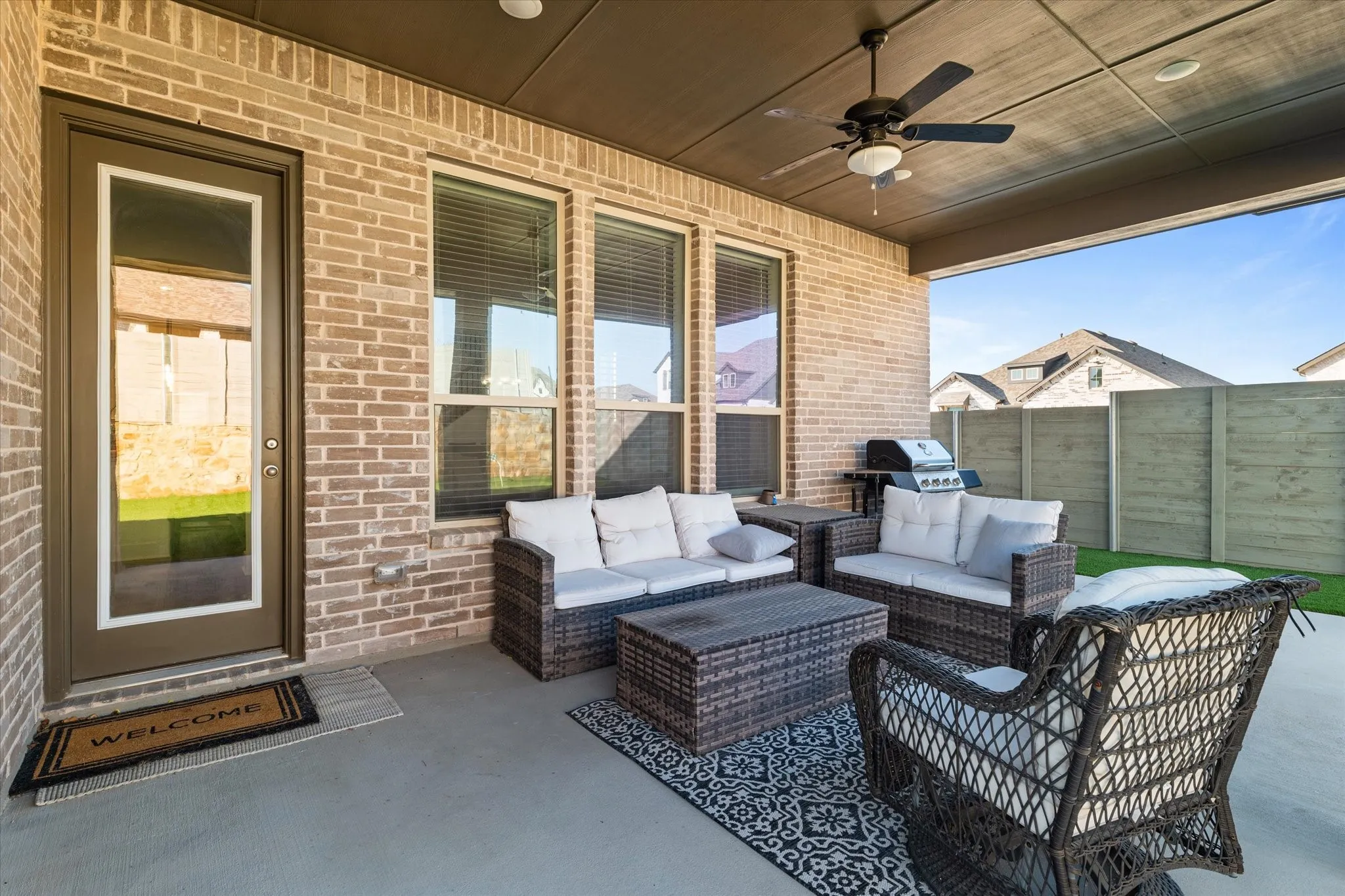 Covered patio with brick wall, concrete flooring, and ceiling fan