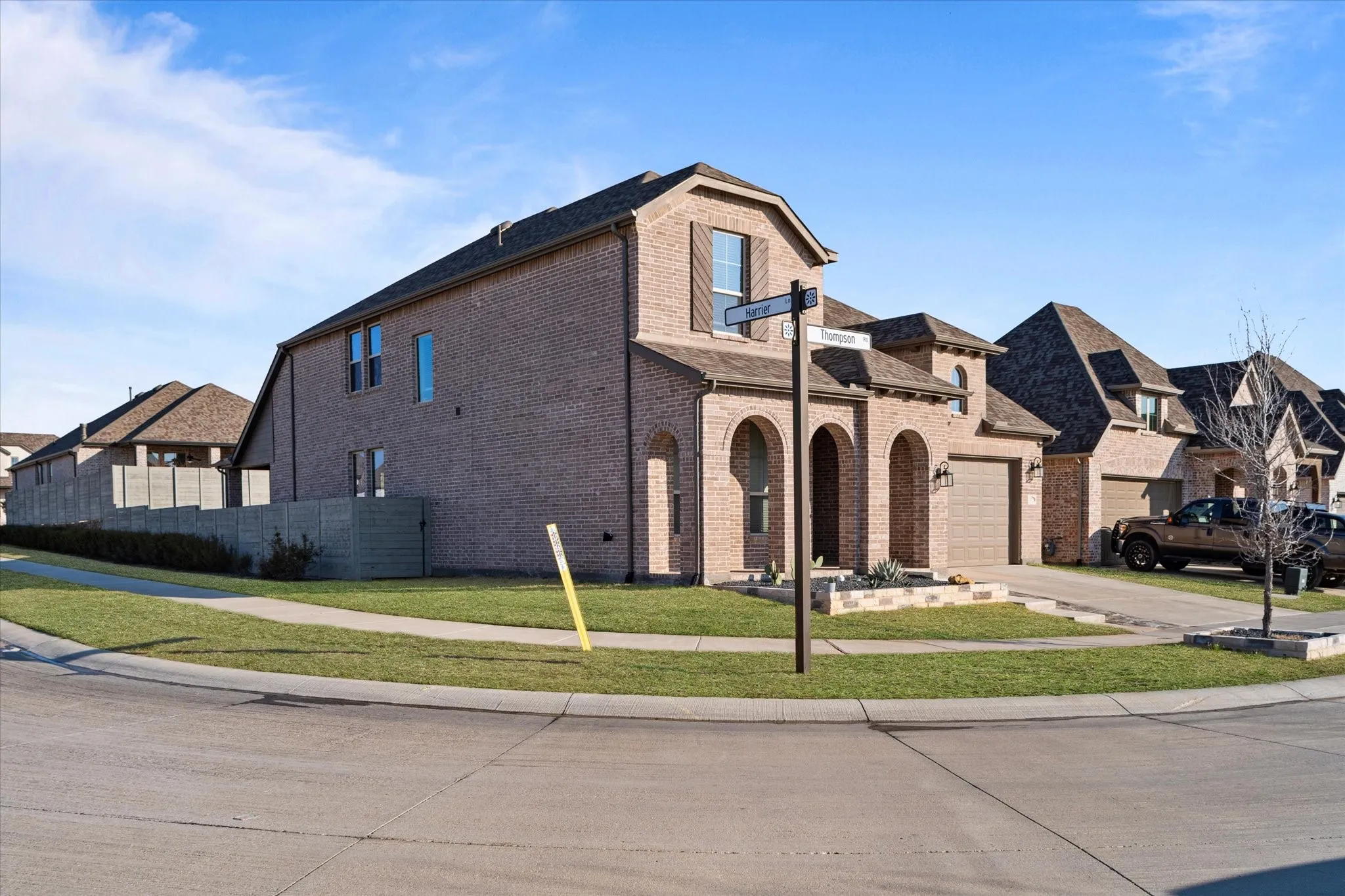 Brick exterior with arched entryways, attached two-car garage, multiple gables, and a concrete driveway