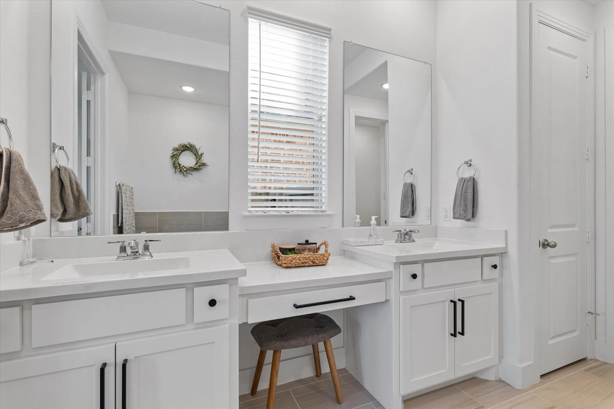 Dual vanity with integrated sinks, white countertops, built-in makeup vanity, and white cabinetry with matte black hardware