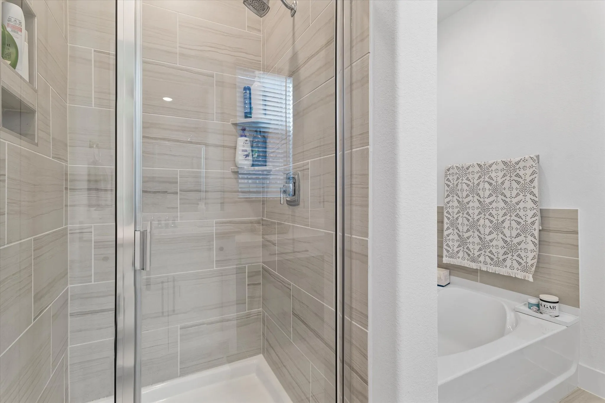 Shower enclosure with full-height tile surround, integrated shower niches, and a rainfall showerhead