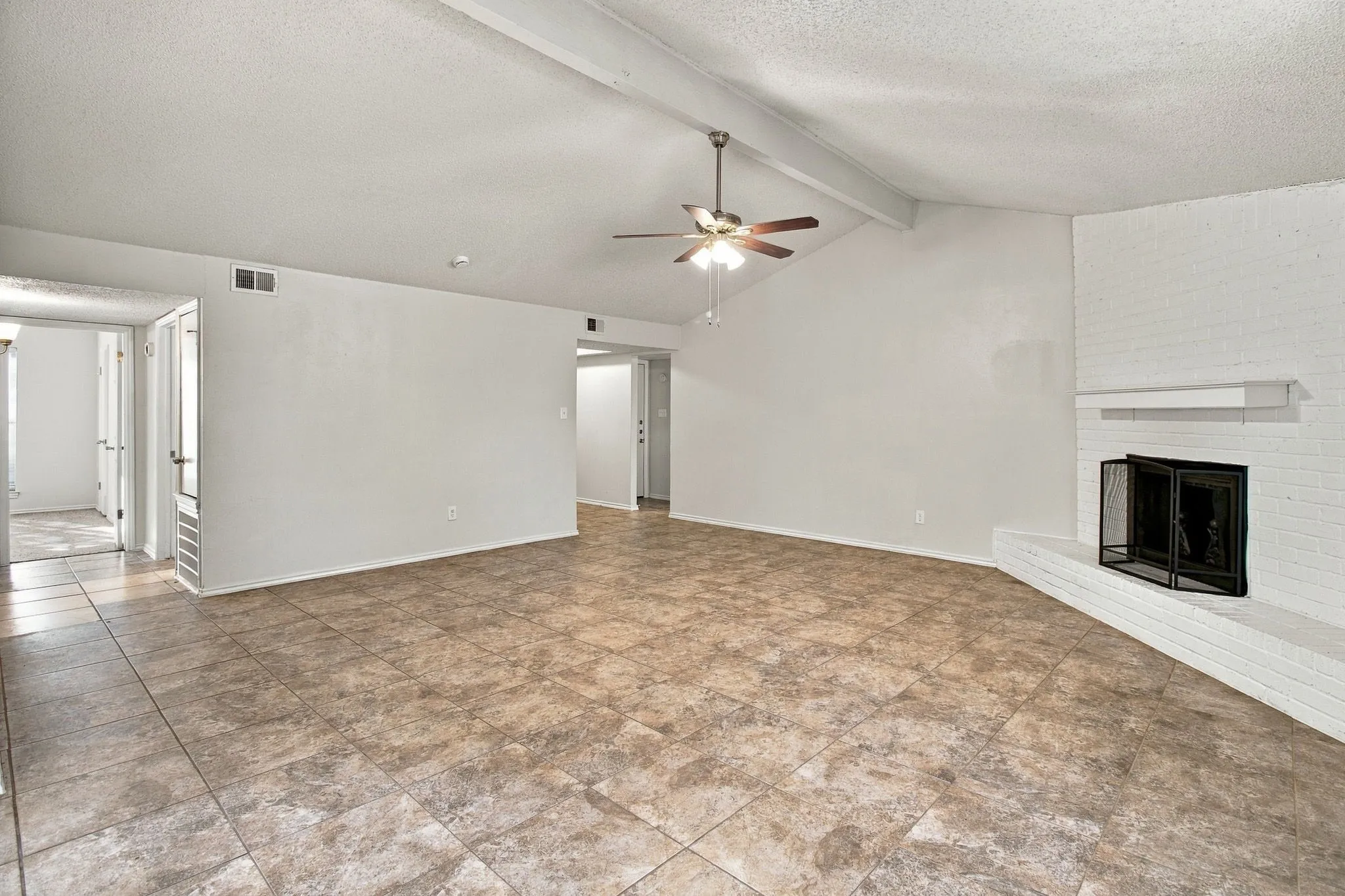 Vaulted ceilings with exposed beams, ceiling fan, and tile flooring
