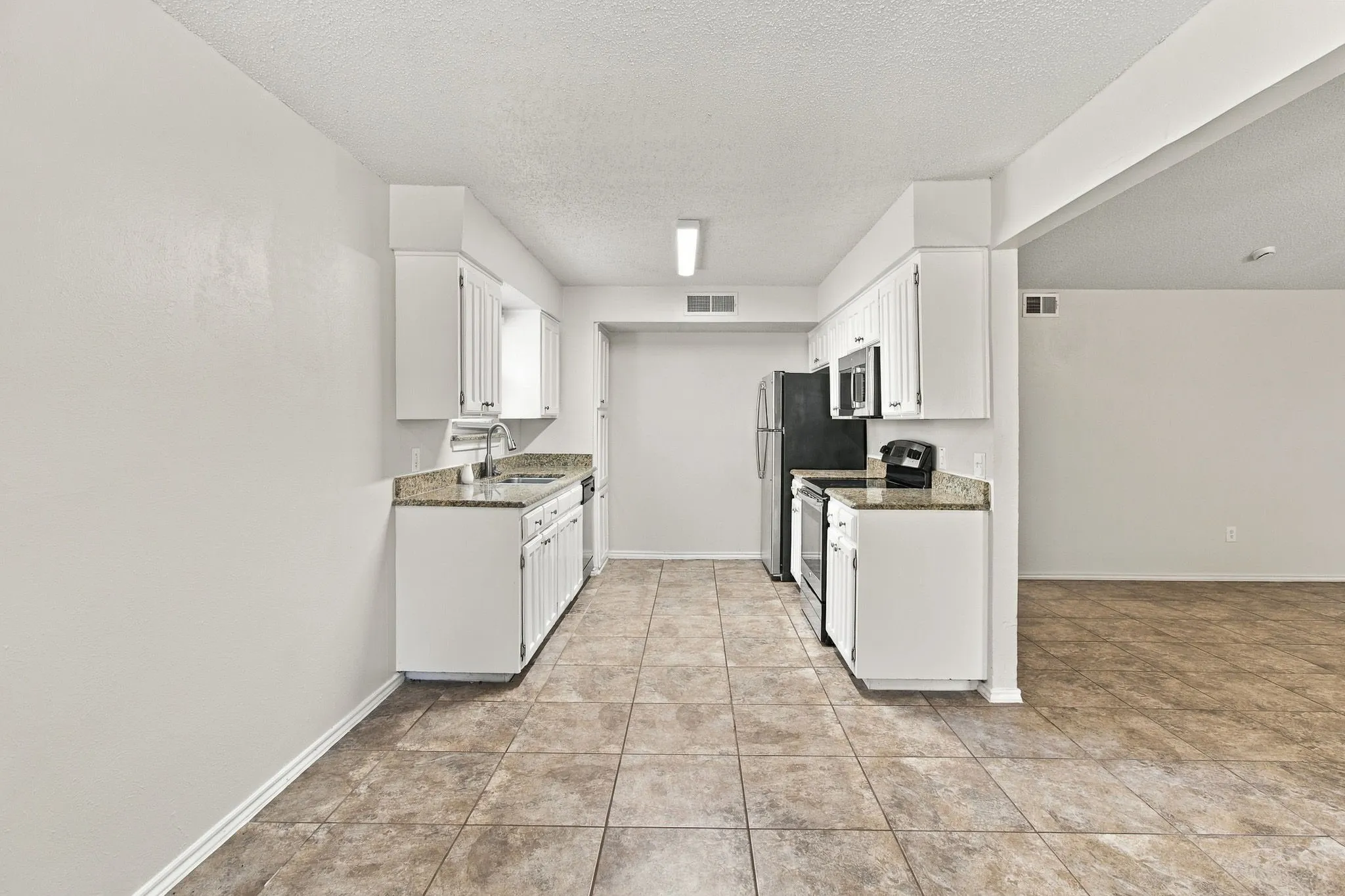 Kitchen featuring white cabinetry, granite-finish countertops, and tile flooring