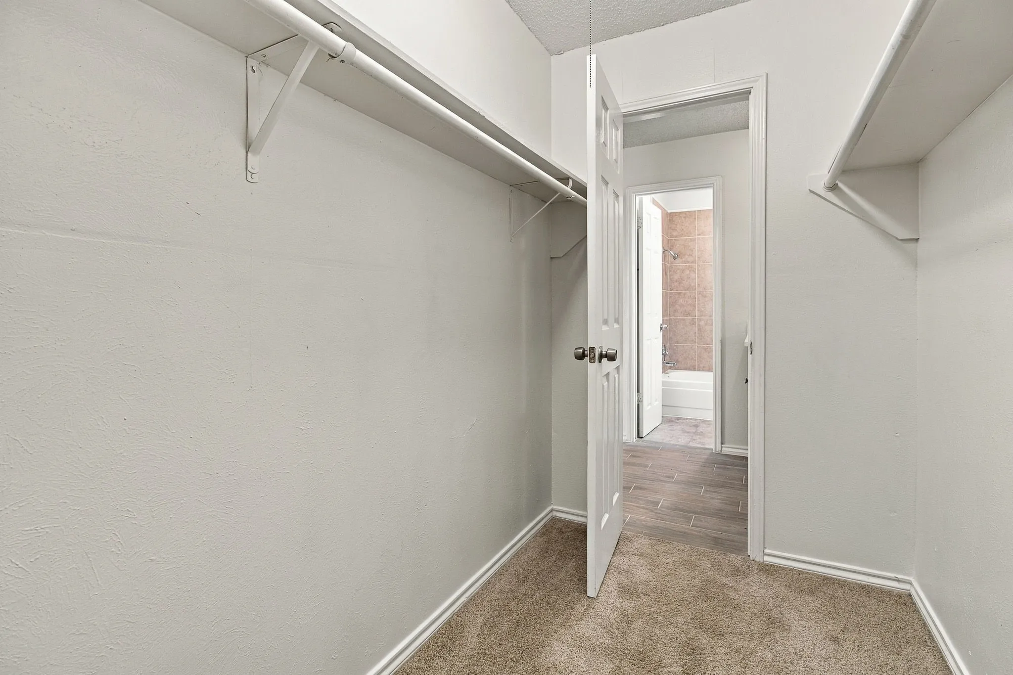 Spacious walk-in closet featuring dual clothing rods, shelving, and wood-finish flooring throughout