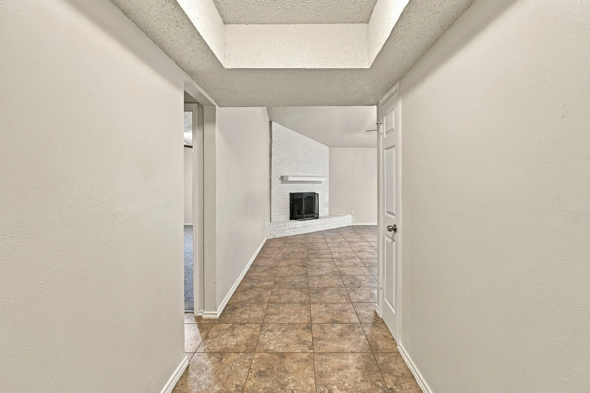 Hallway featuring textured walls, tile flooring, and a recessed ceiling detail