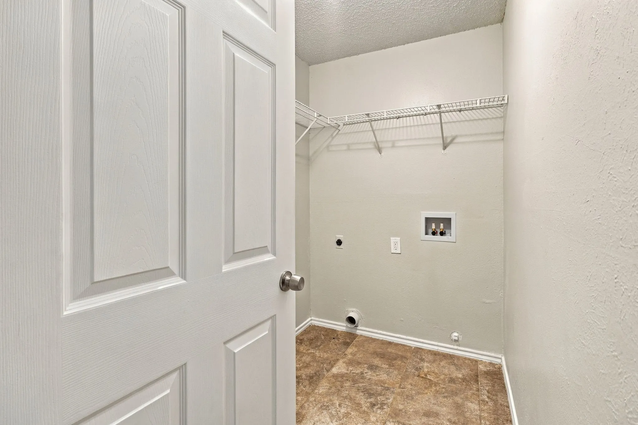 Utility area featuring wire shelving, tile flooring, and appliance hookups