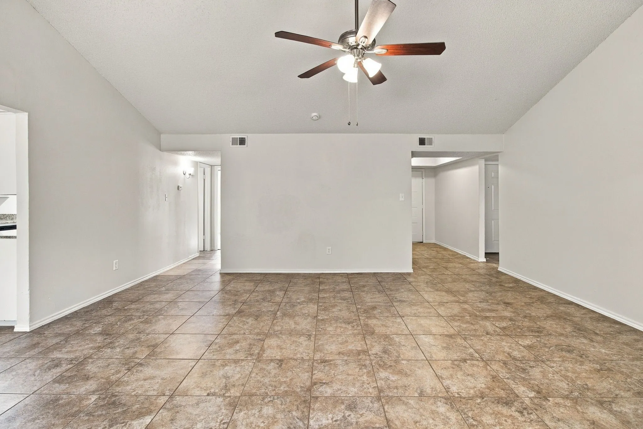Vaulted ceiling with a ceiling fan, tile flooring, and neutral wall tones