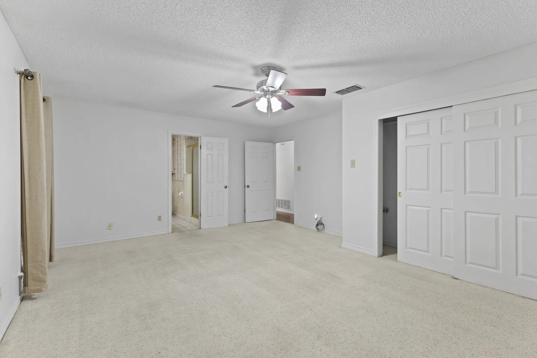 Carpeted flooring, ceiling fan, and sliding panel closet doors