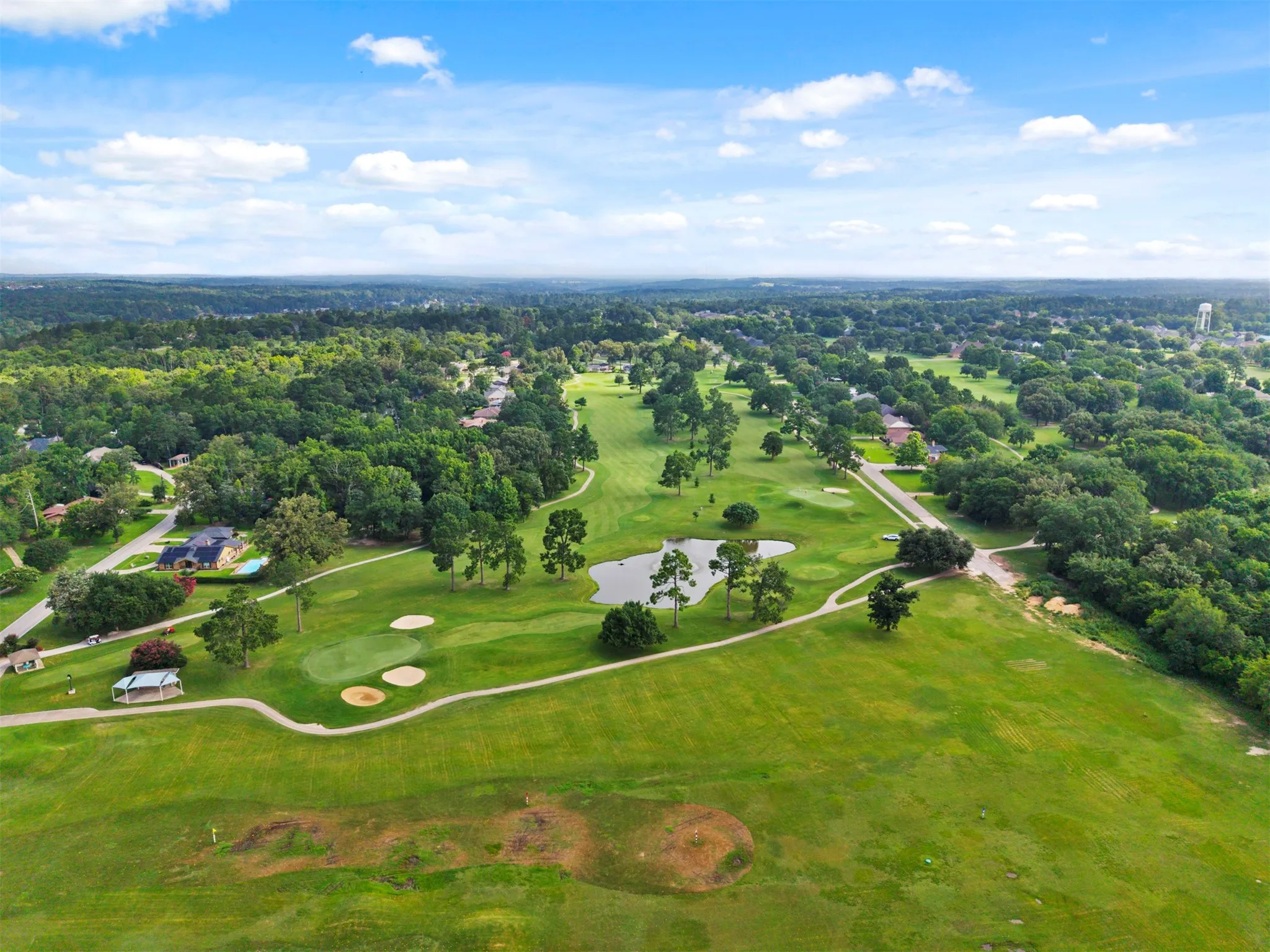 Expansive green spaces with a golf course, mature trees, and a tranquil pond