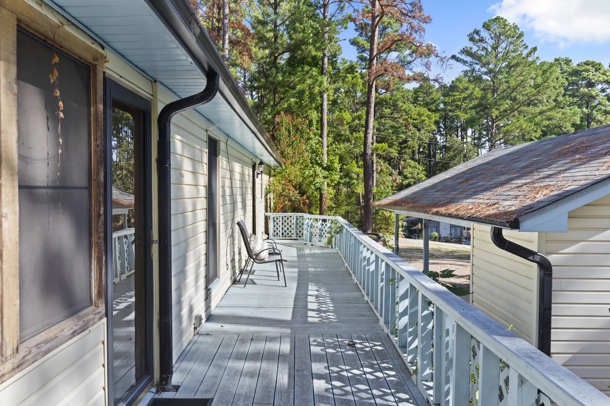 Expansive wood deck with lattice railing, multiple exterior doors, and full-length gutters