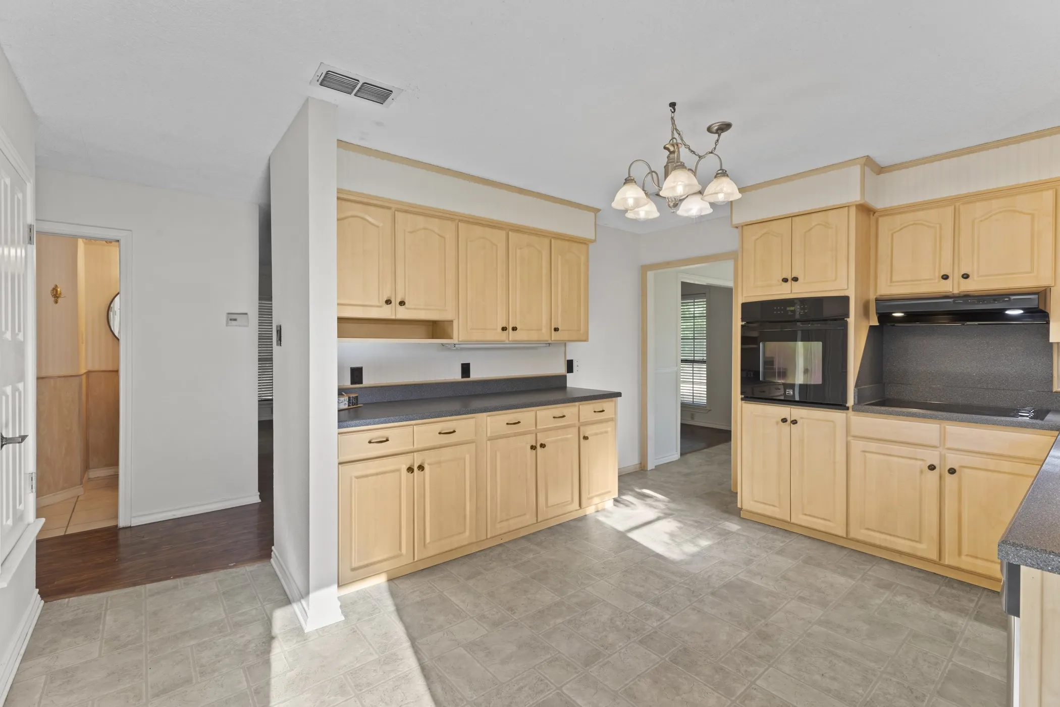 Kitchen featuring wood-finish cabinetry, dark countertops, built-in wall oven, and tile flooring