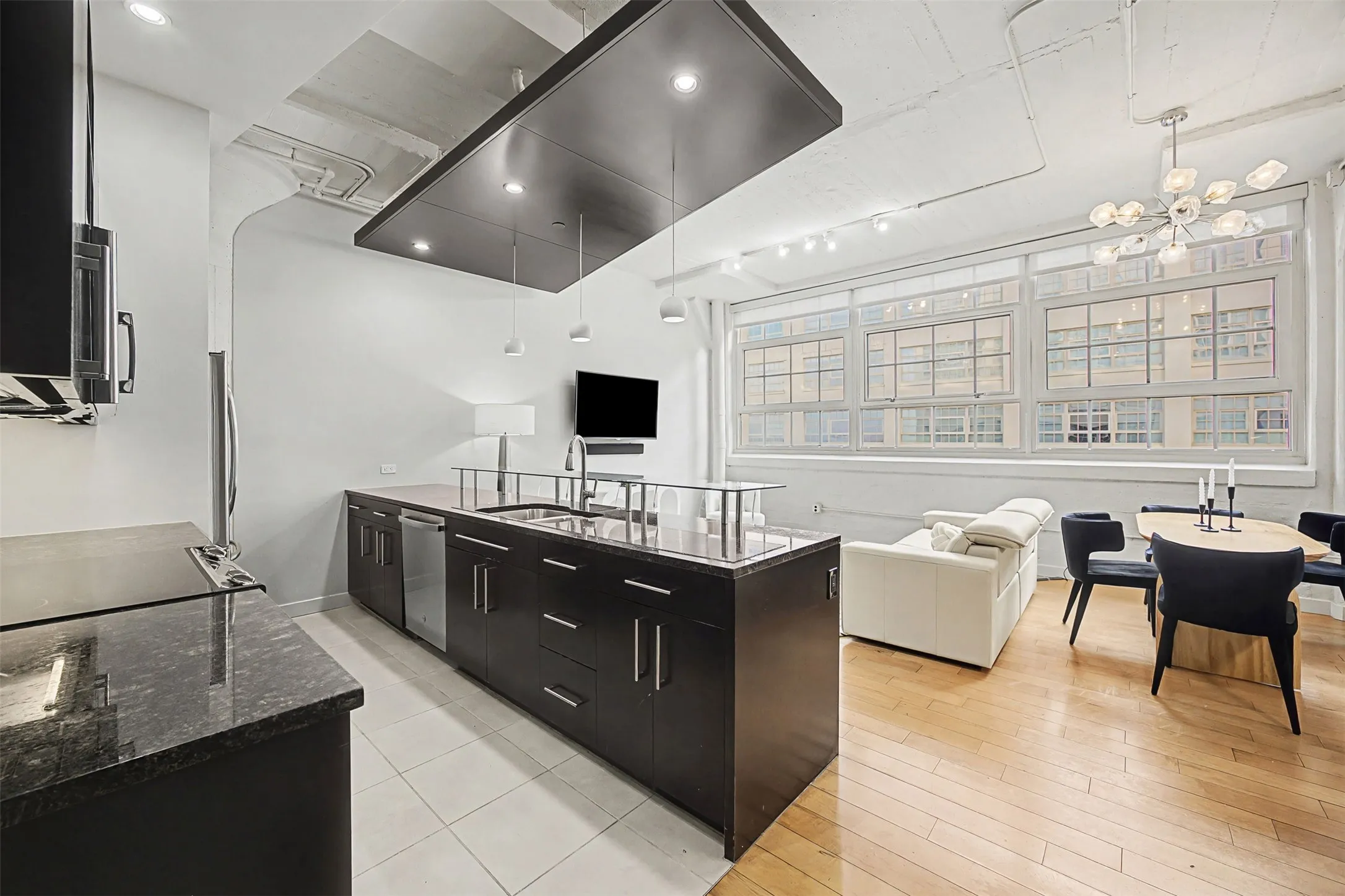 Kitchen with dark cabinetry, modern cabinets, dark stone countertops, and open floor plan