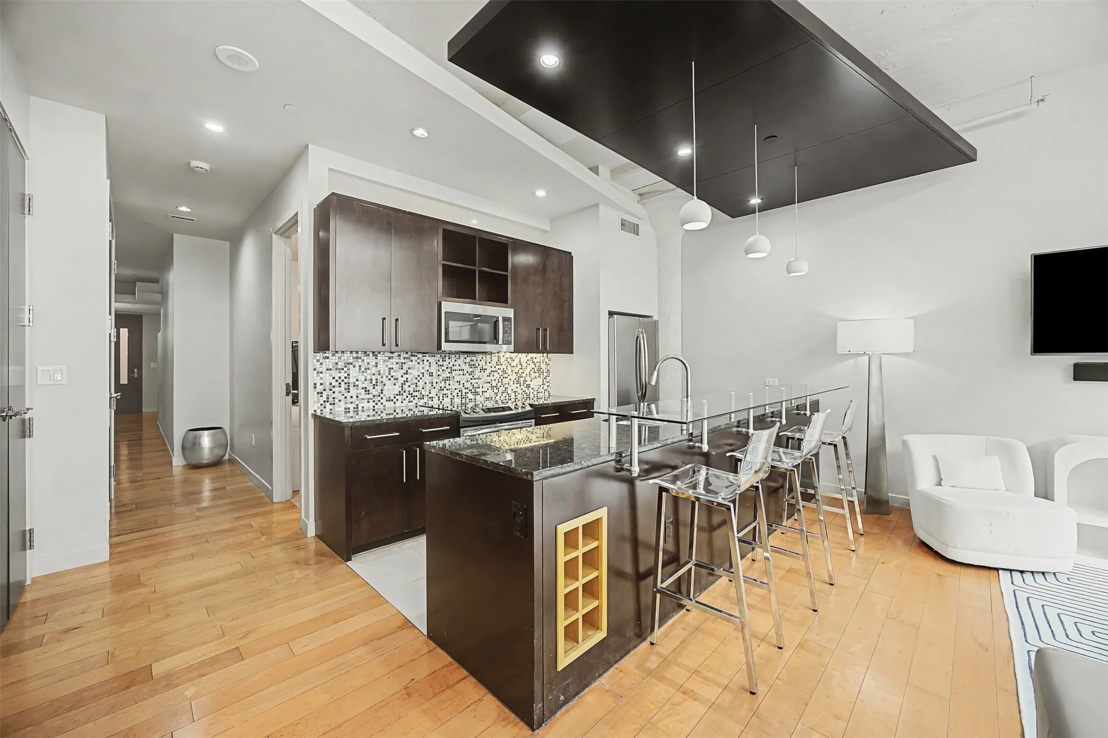 Kitchen featuring dark wood finish cabinets, light wood-style flooring, a kitchen breakfast bar, a large island, and modern cabinets