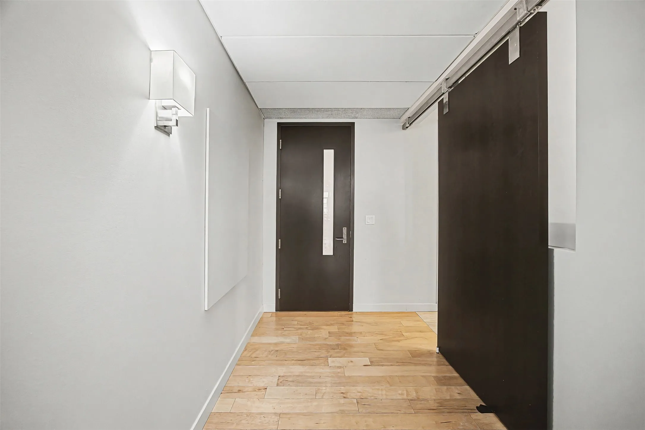Hall with light wood-type flooring and a barn door