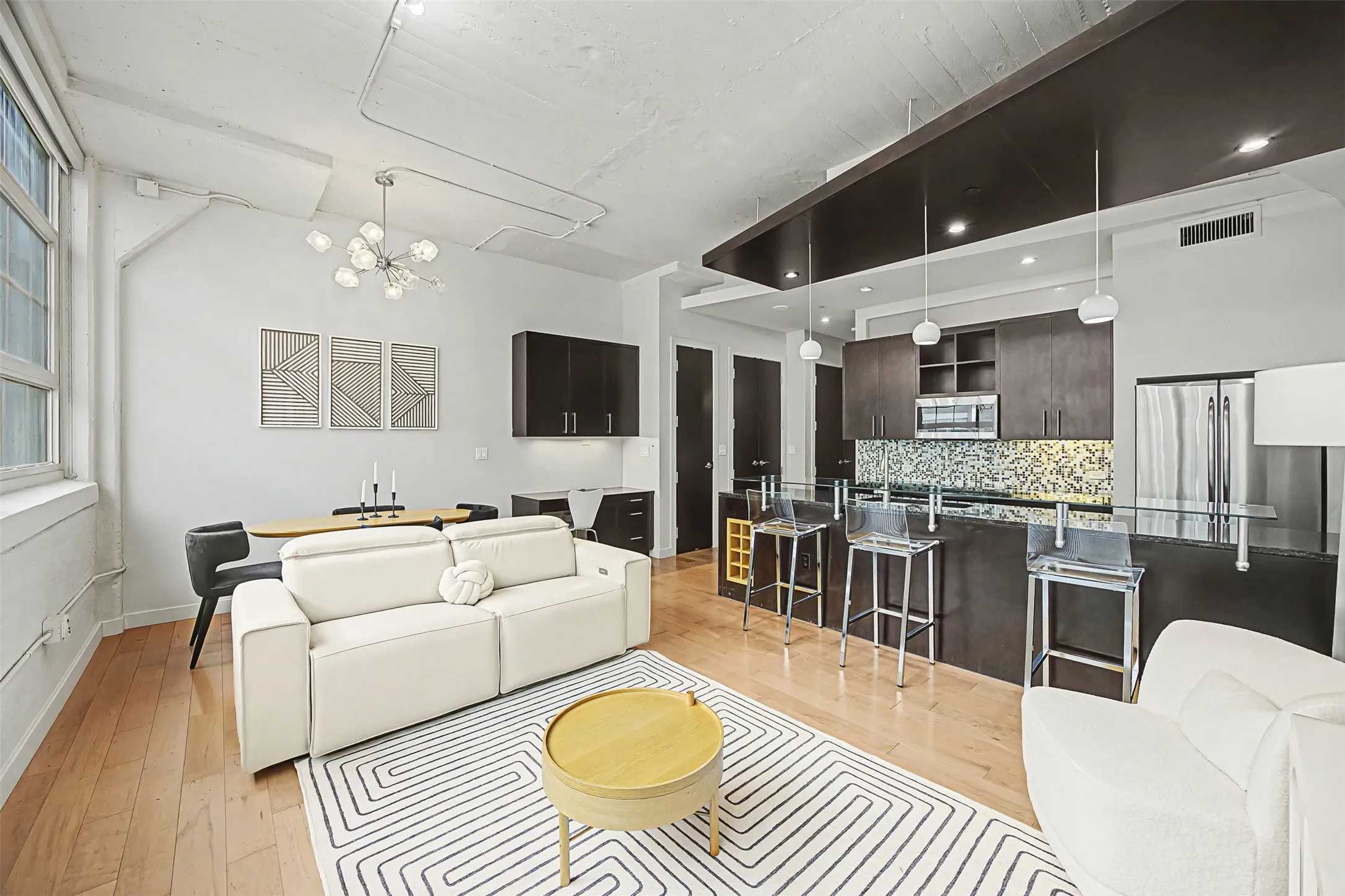 Living room with light wood-style flooring and hanging lights