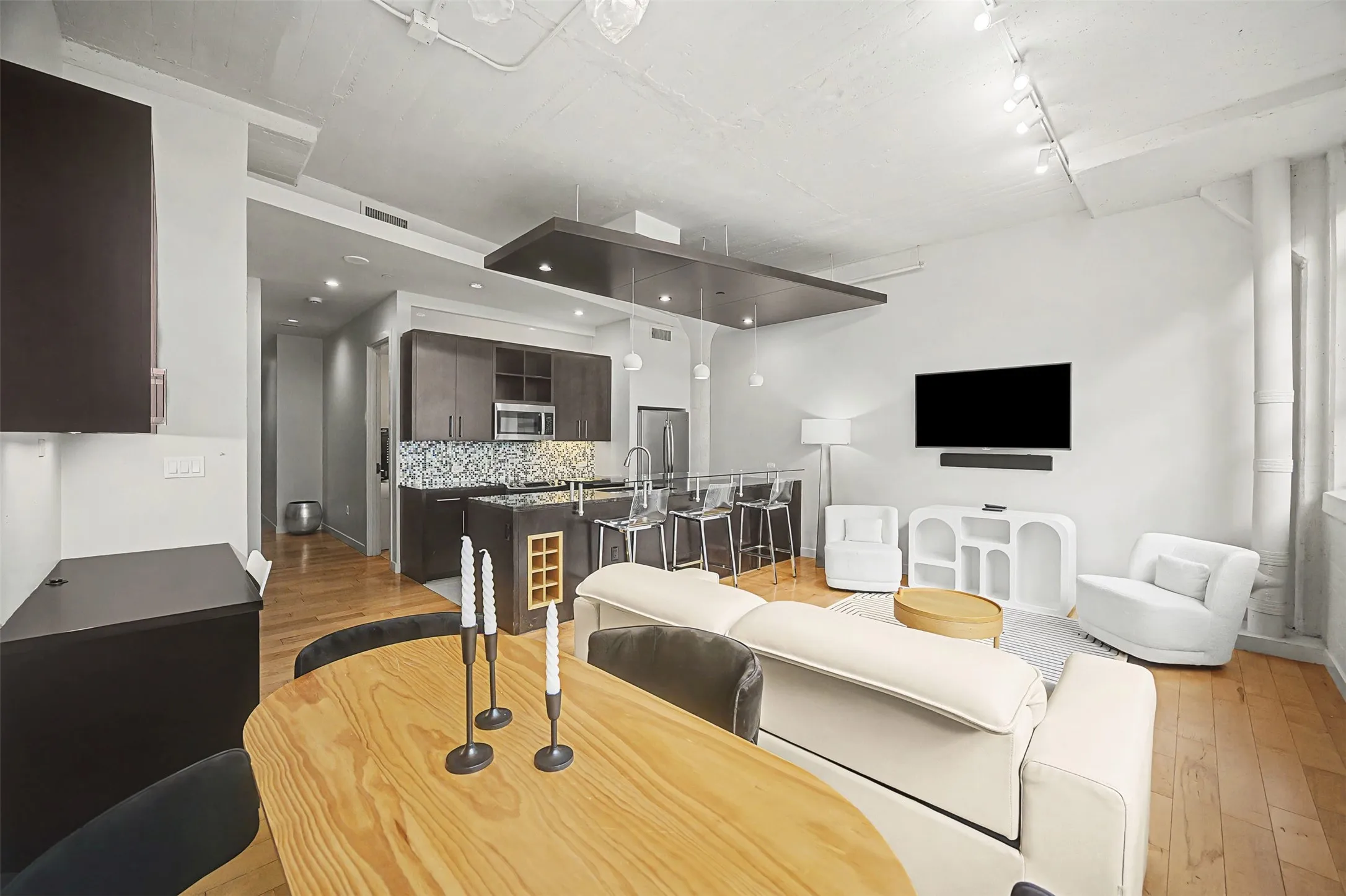 Living area with light wood finished floors and rail lighting