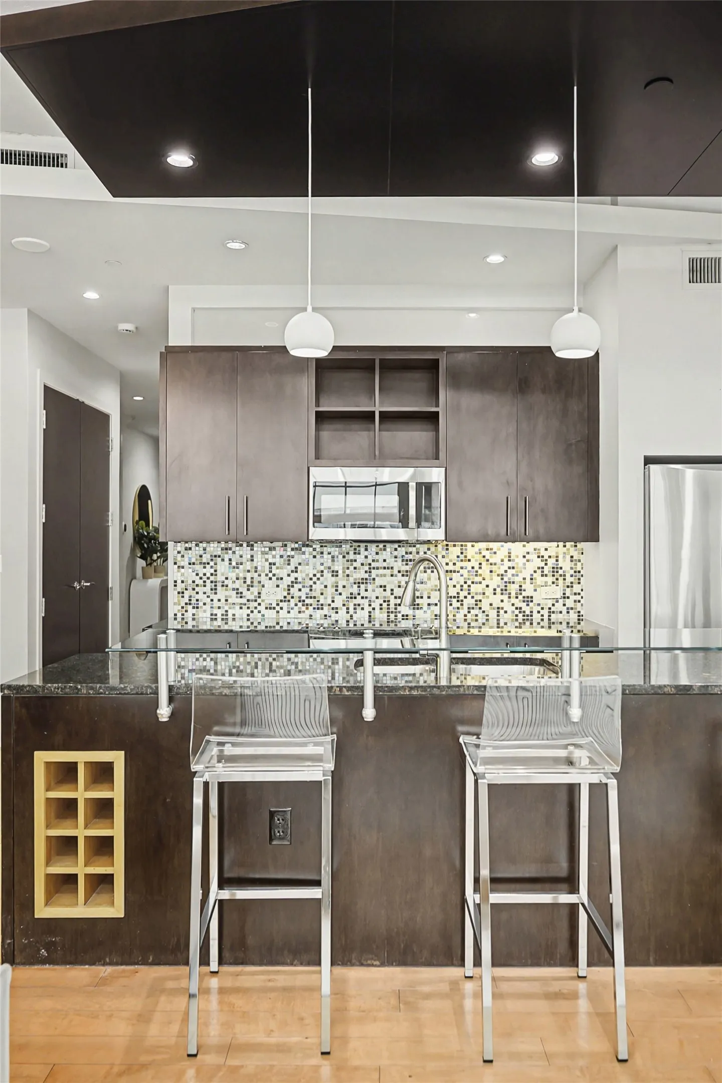 Kitchen featuring a kitchen bar, dark wood finish cabinetry, open shelves, and stainless steel appliances