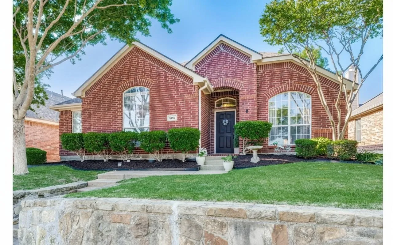 Brick exterior with arched window details, prominent entry archway, manicured front lawn, stone retaining wall, and mature trees
