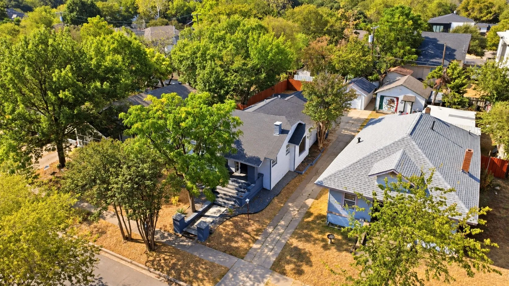 Pitched shingle roofing, mature trees, and a concrete driveway