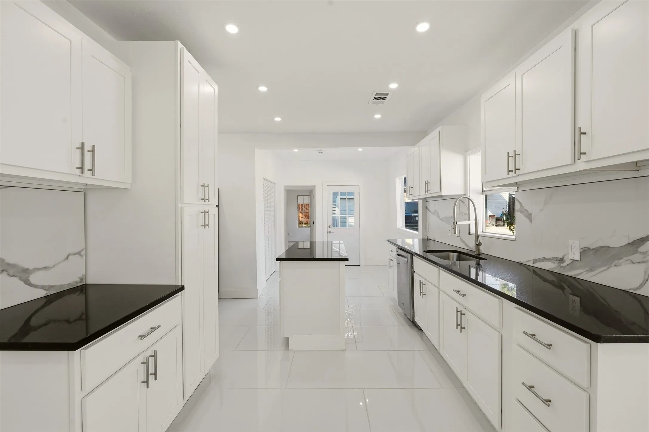 Modern kitchen featuring white shaker cabinetry, dark countertops, a center island, recessed lighting, and white tile flooring