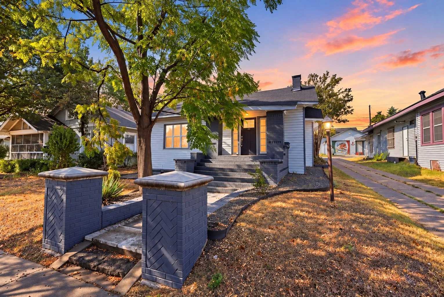 Exterior featuring light-colored siding, a dark trim entry, and concrete steps with mature front yard trees