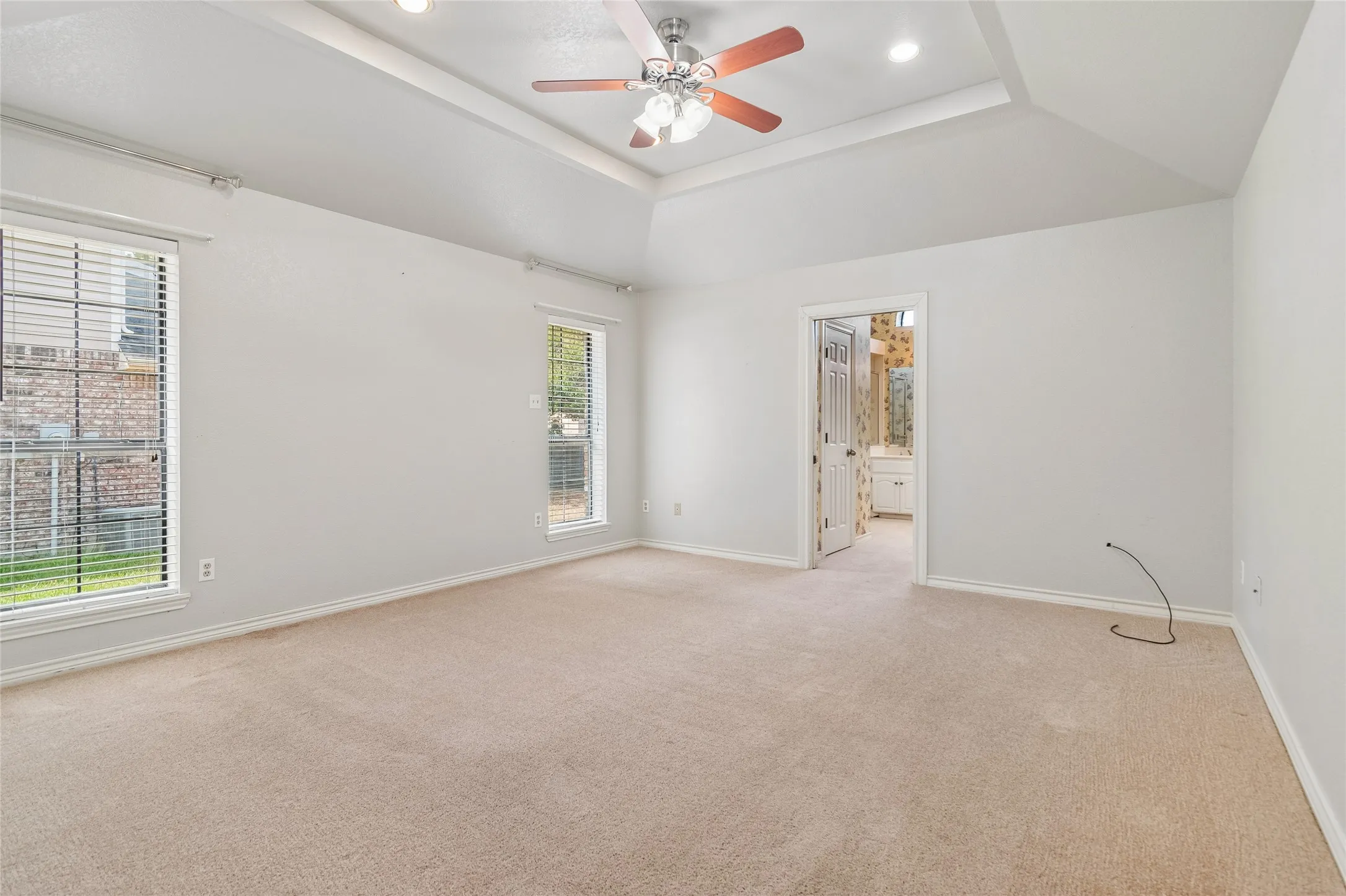 Tray ceiling with recessed lighting, ceiling fan with light kit, and carpeted flooring