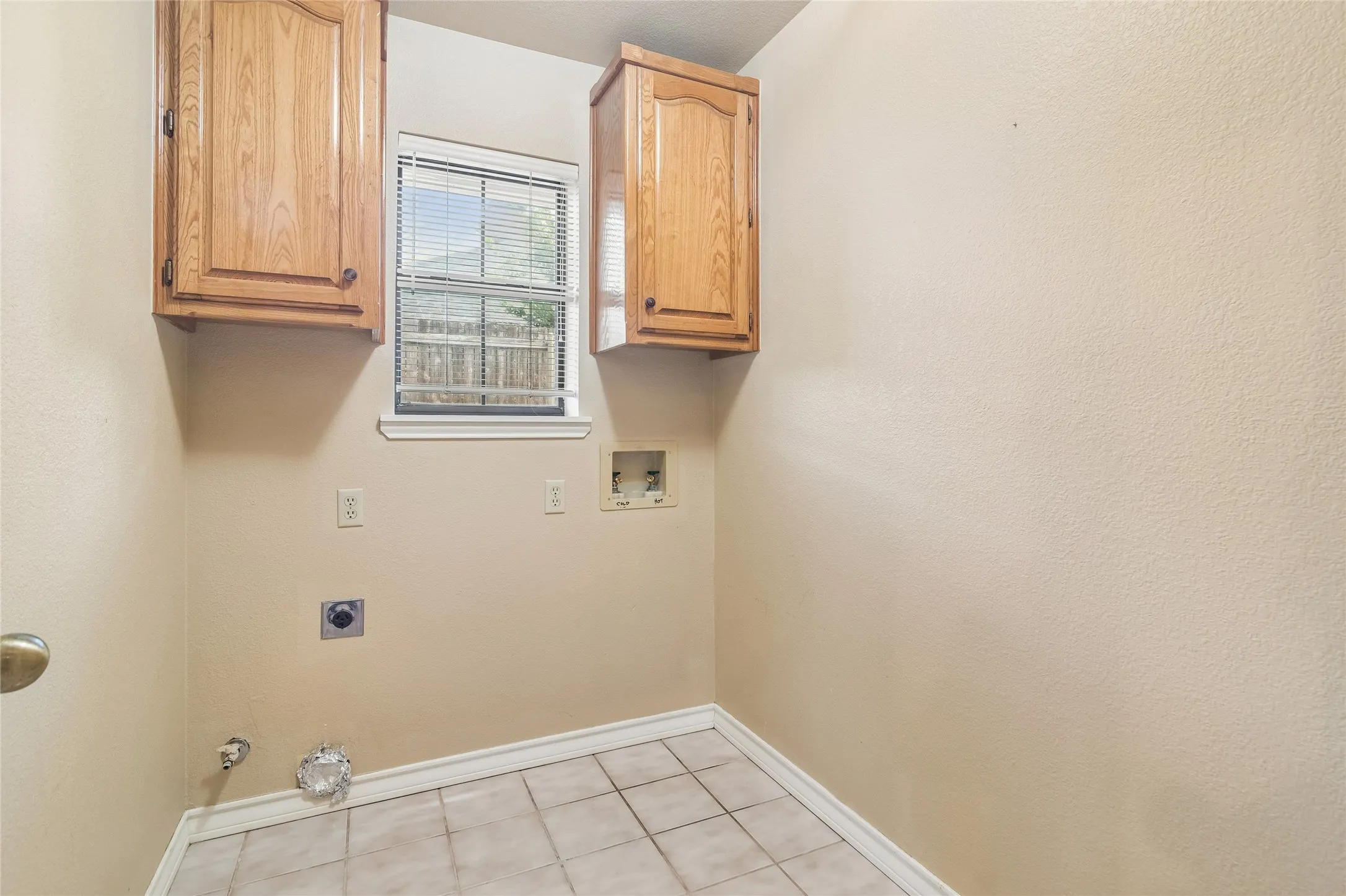 Tile flooring, two wood-finish wall cabinets, and a window with blinds