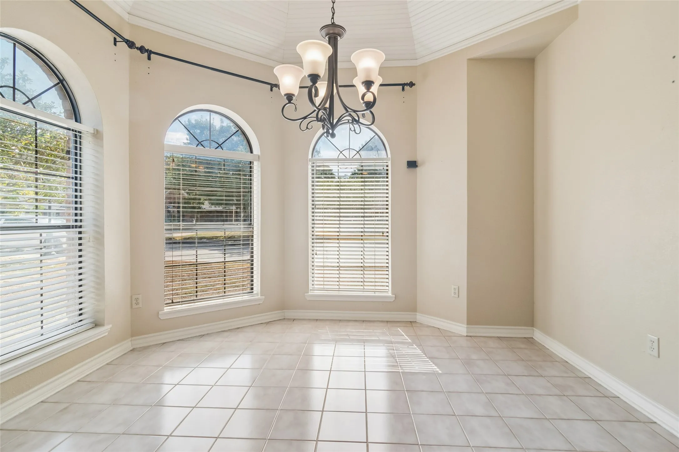 Arched windows, tile flooring, pendant light fixture, coved ceiling, and crown molding