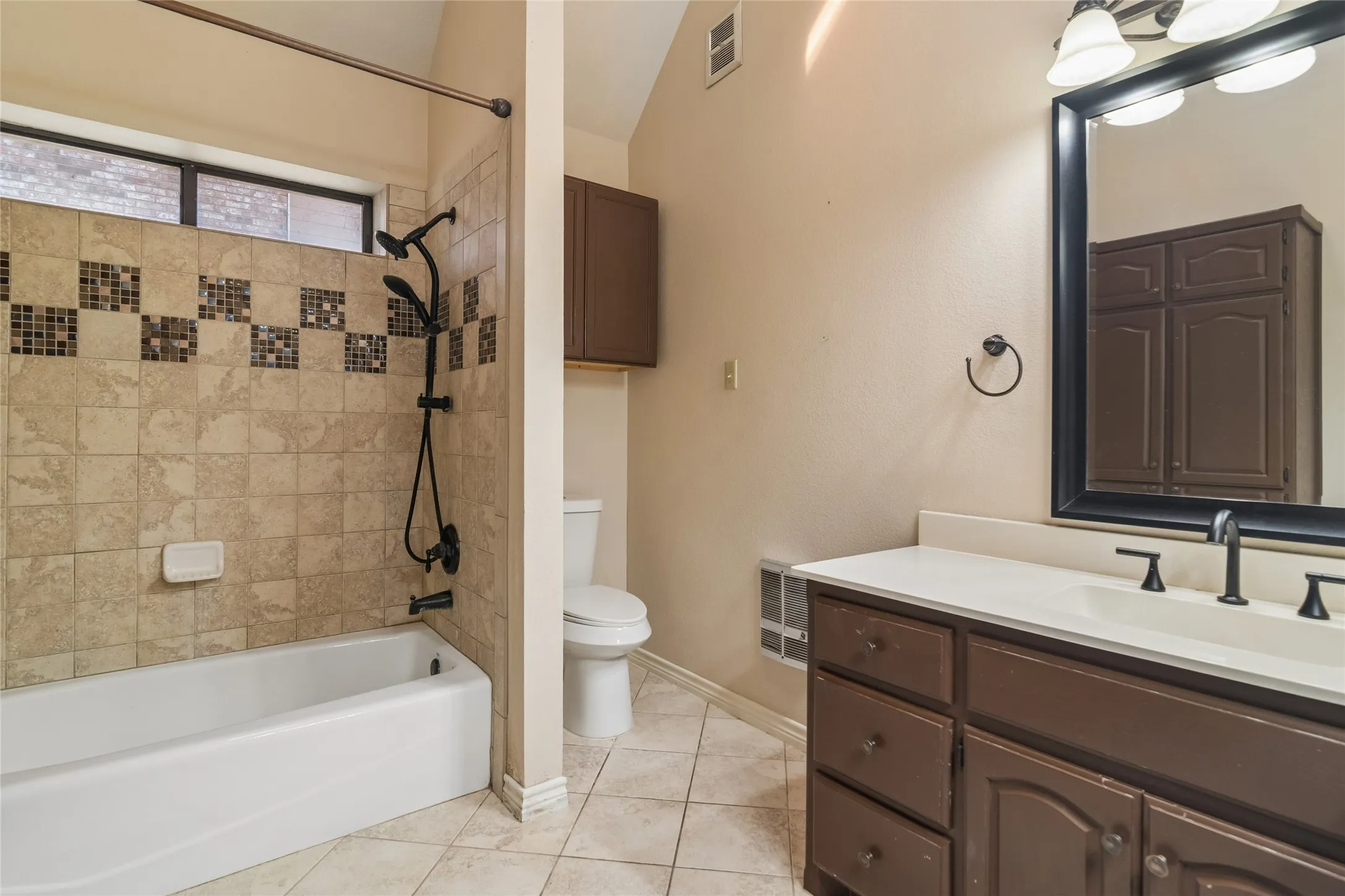Tiled shower and tub combination featuring a mosaic accent band, a dual-head matte black shower system, and an elevated window
