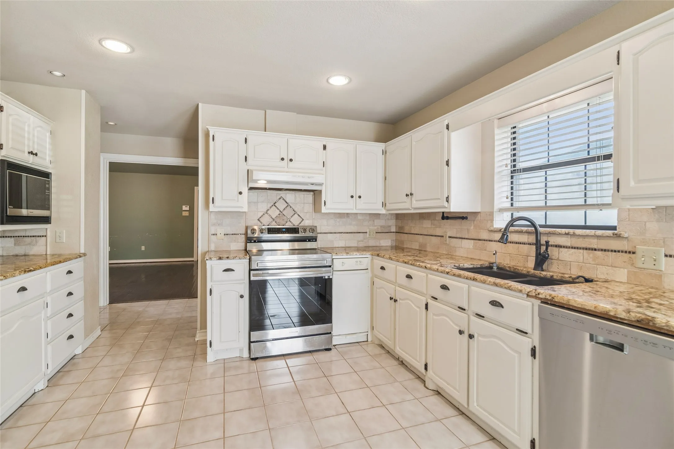 Kitchen featuring white cabinetry, stainless steel appliances, granite countertops, a tiled backsplash, and recessed lighting