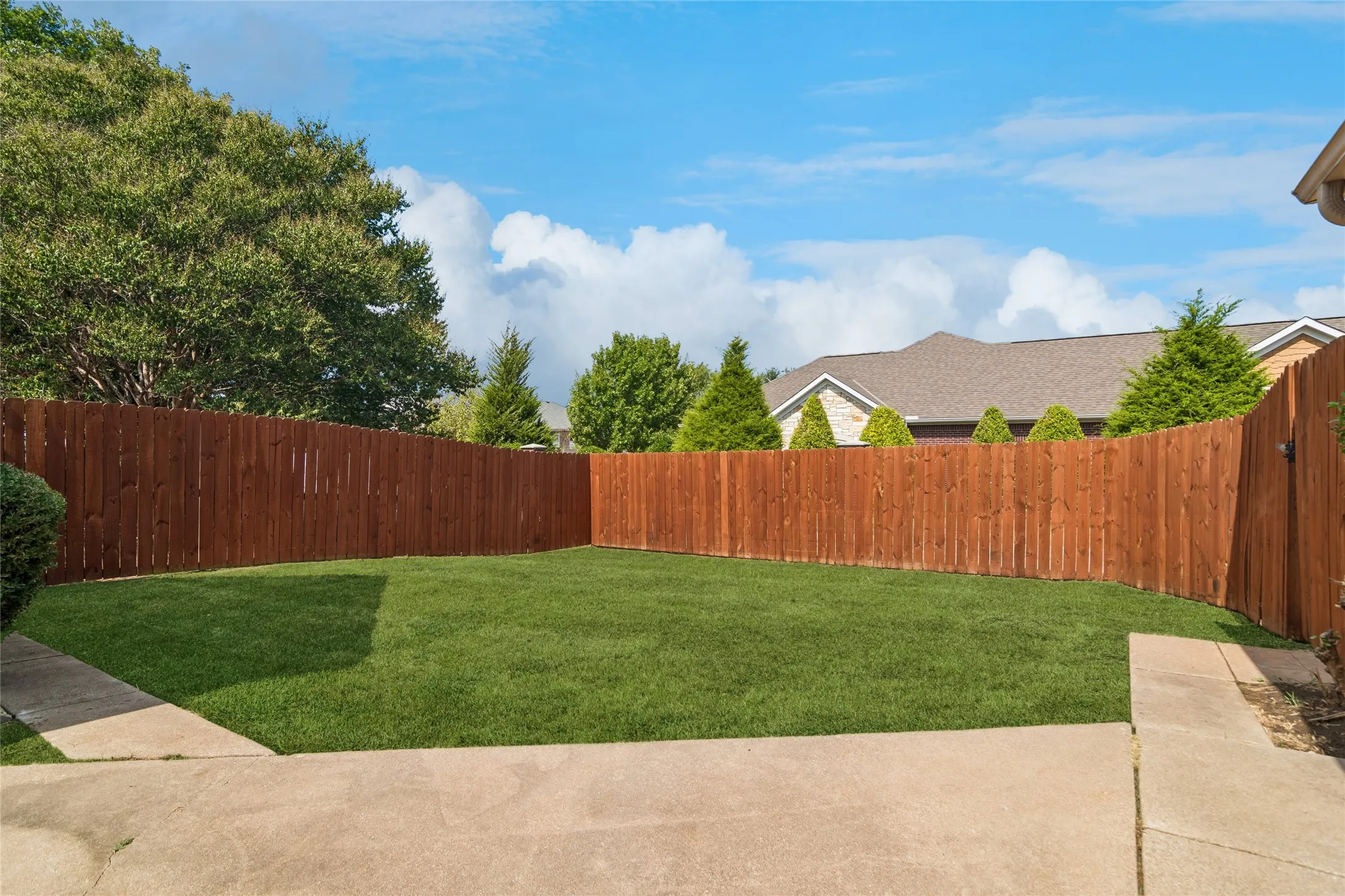 Expansive outdoor area featuring a privacy fencing, and concrete pathways
