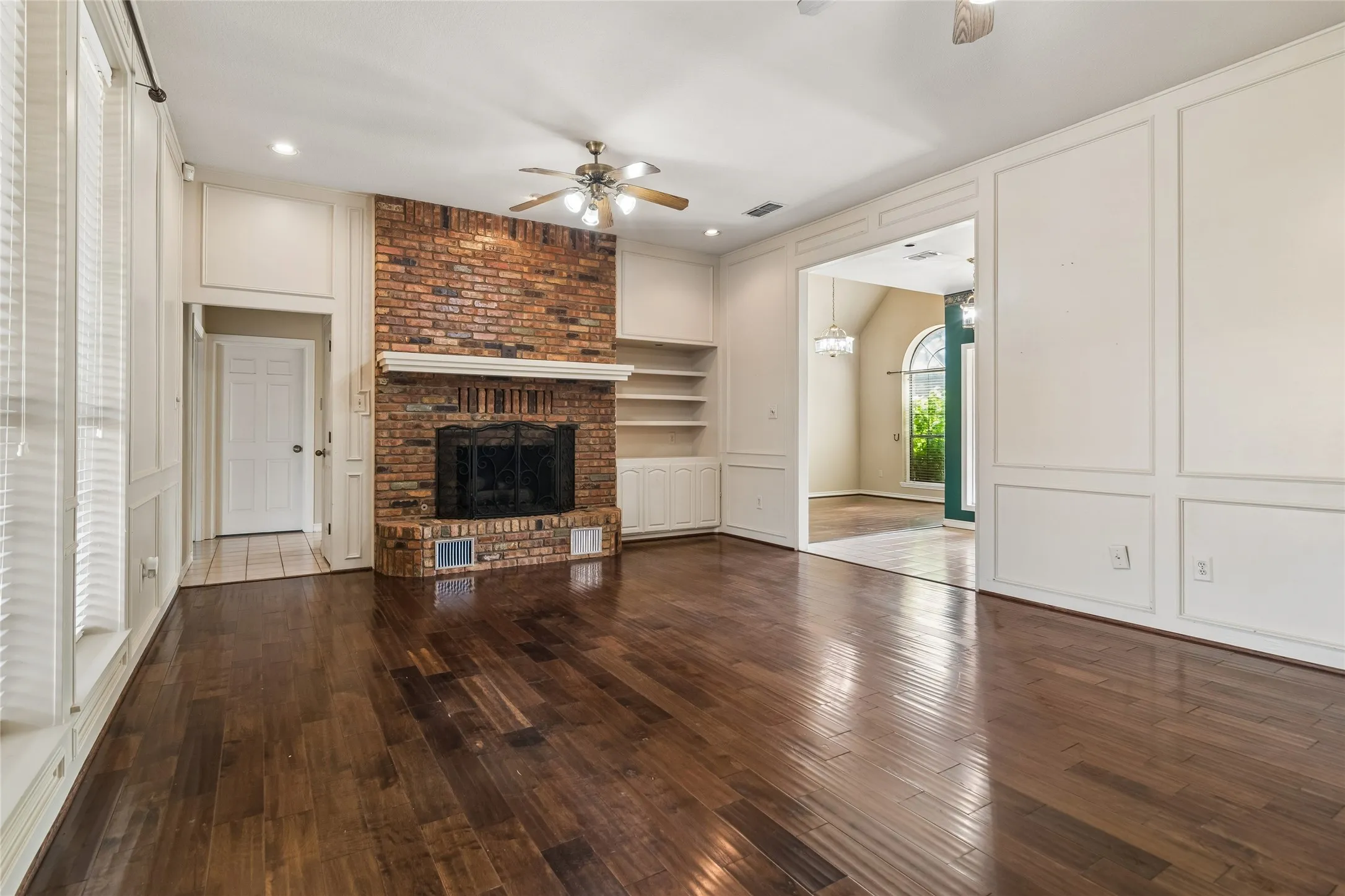 Brick fireplace with a white mantel, wood-finish flooring, recessed lighting, and a ceiling fan
