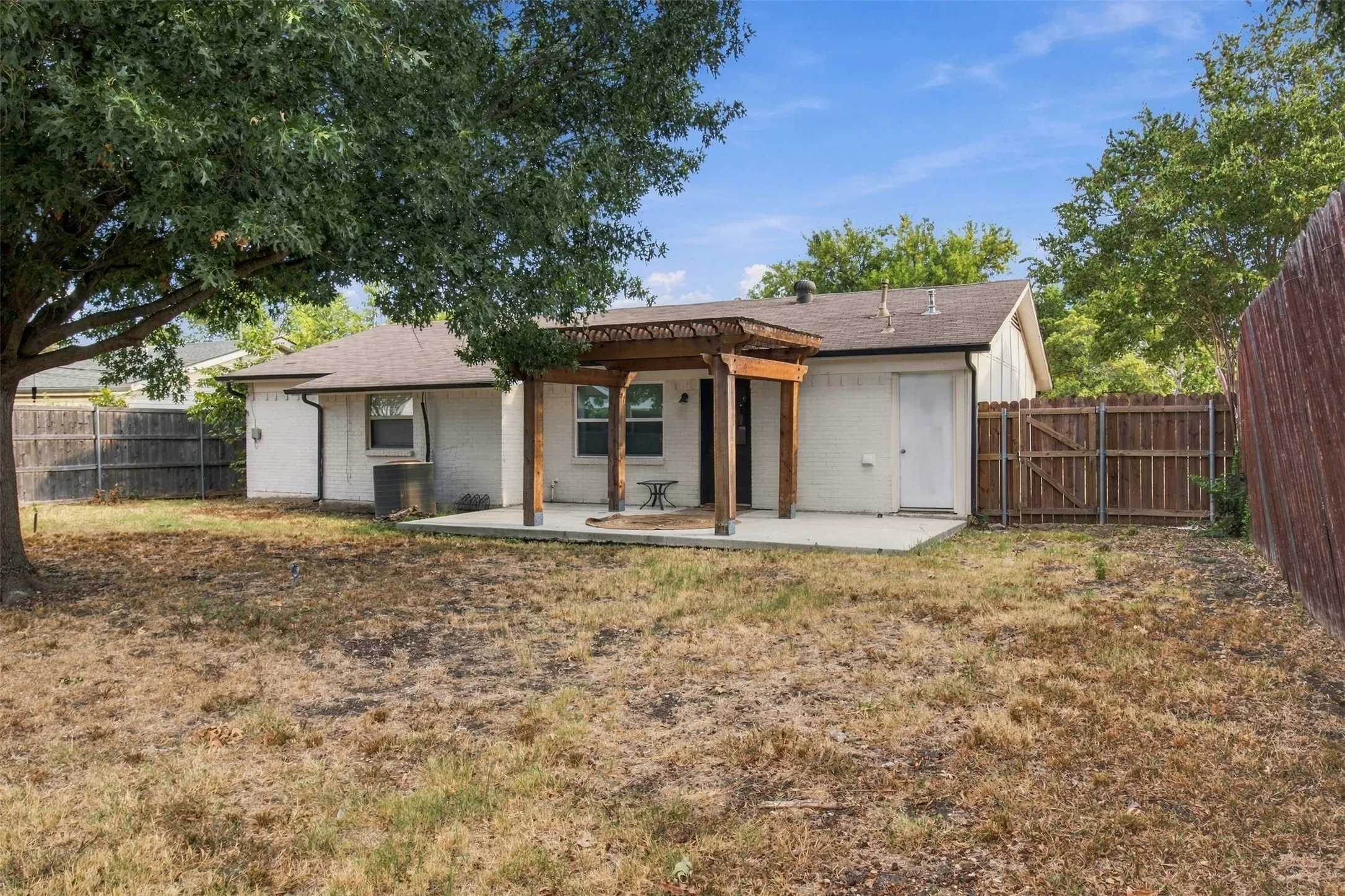 Outdoor living area featuring a pergola-covered patio, concrete slab, and wood privacy fencing