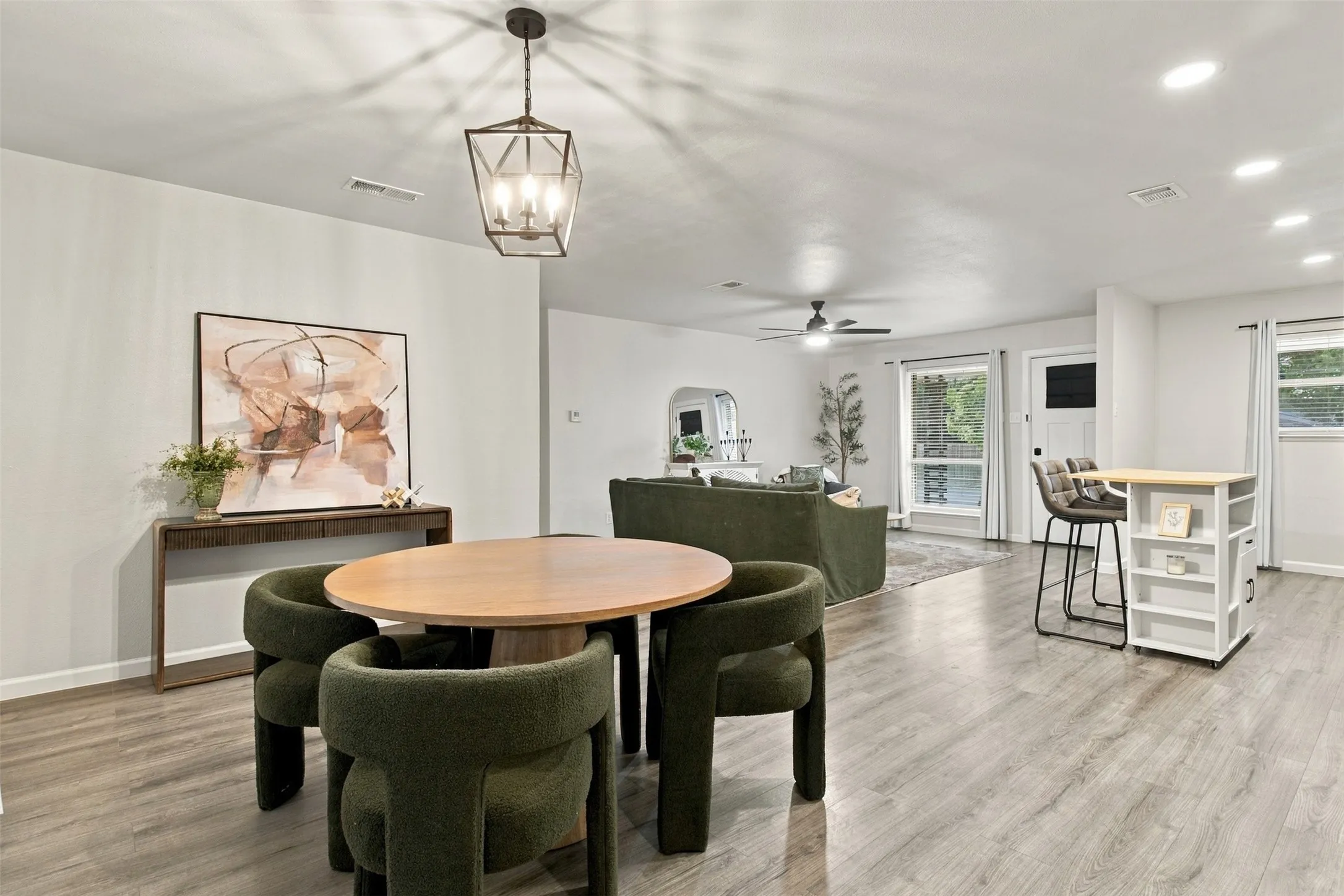 Open-concept living area featuring wood-finish flooring, recessed lighting, and a contemporary chandelier