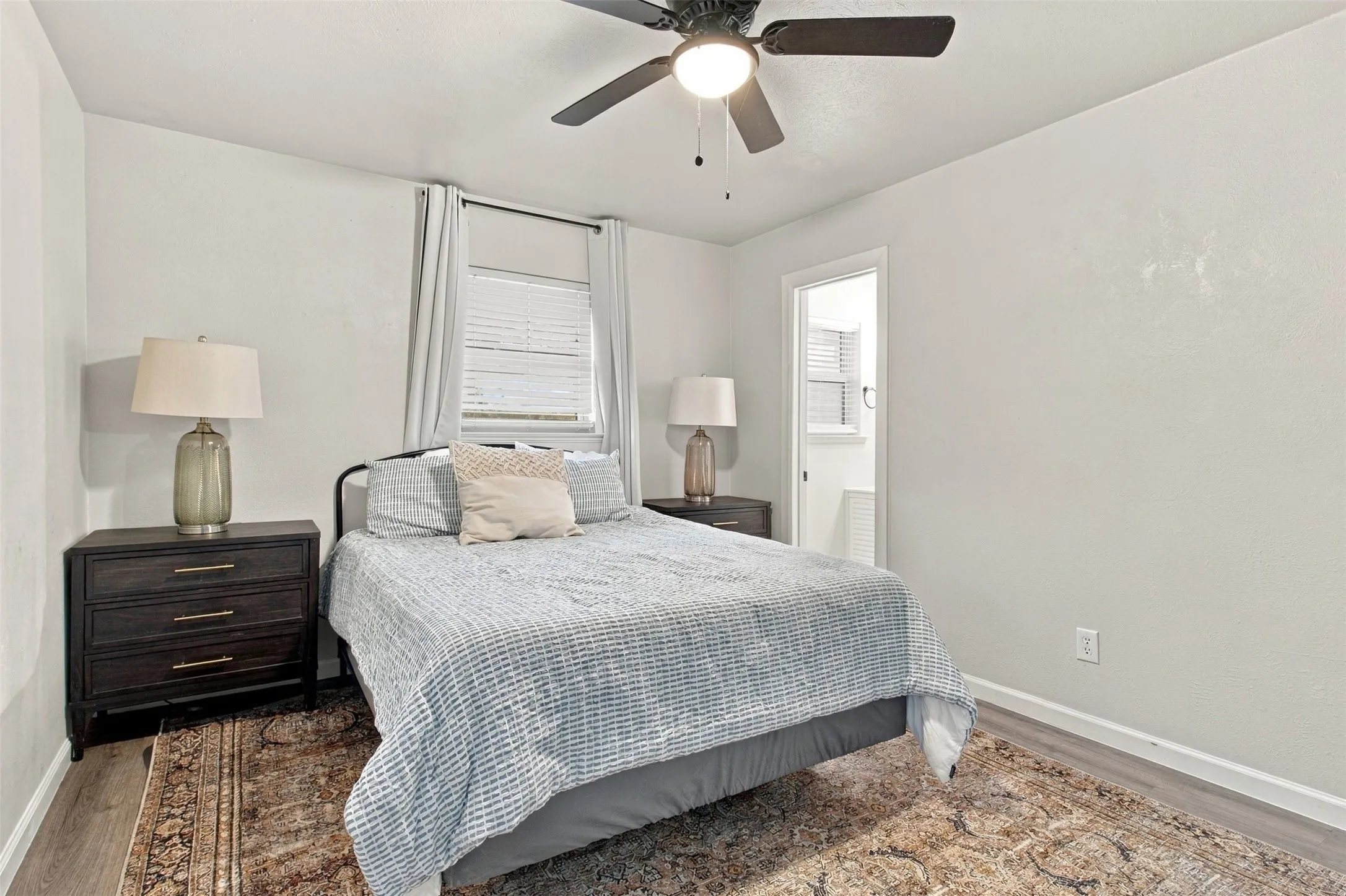 Recessed window with blinds, ceiling fan with integrated lighting, wood-finish flooring, and white painted walls