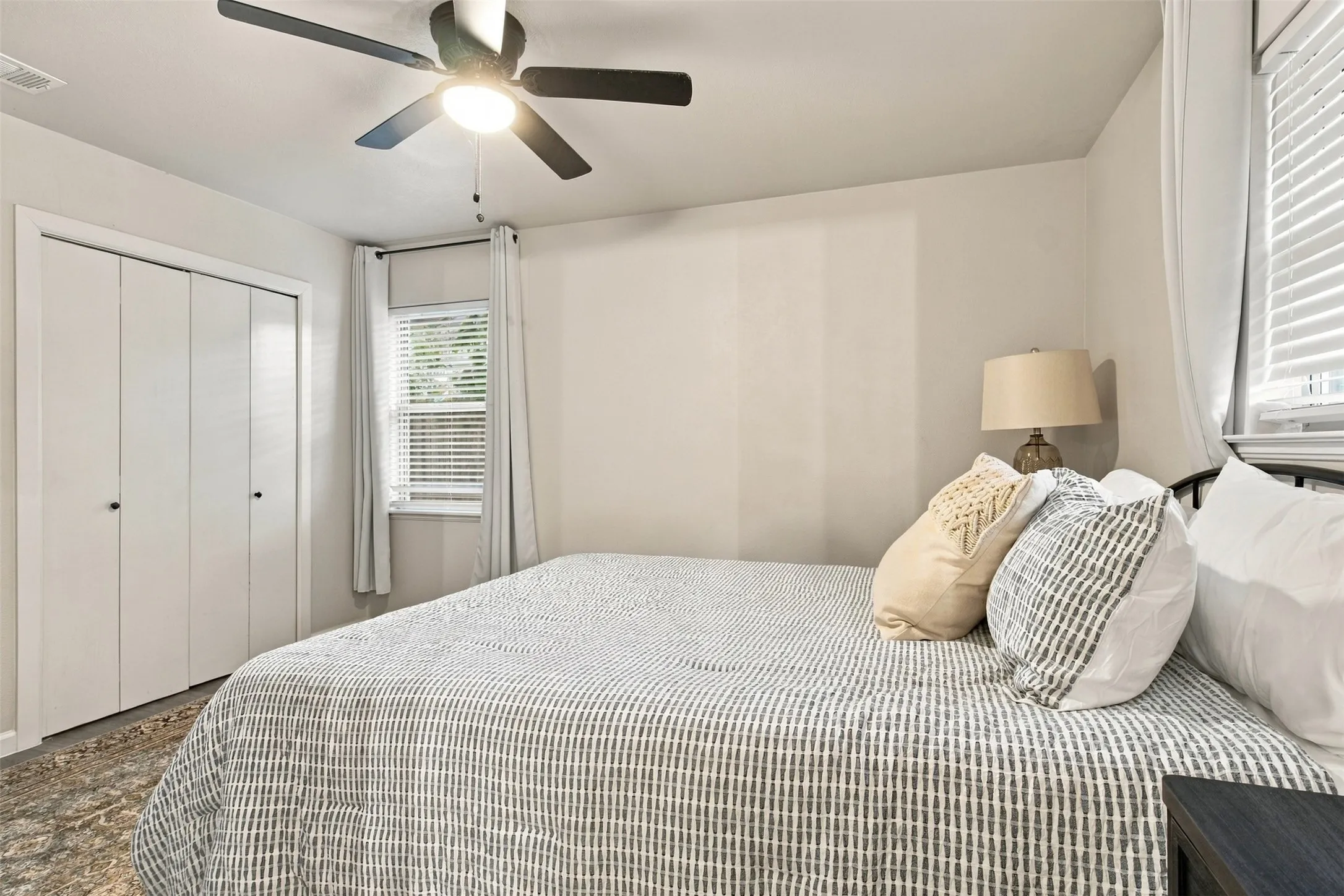 Wall-mounted ceiling fan with light fixture, window with blinds, and bi-fold closet doors