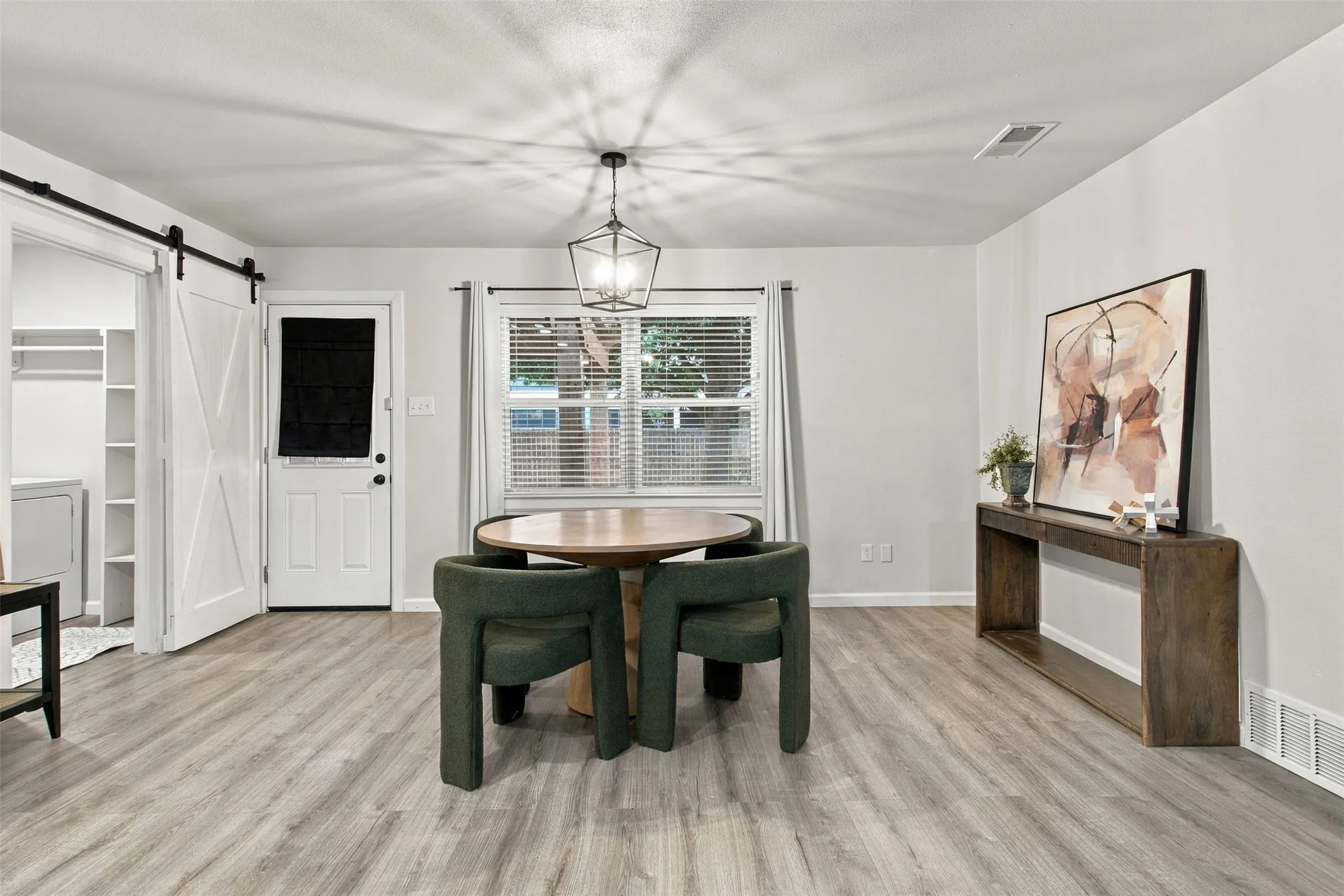 Wood-finish flooring throughout, white interior walls, and a modern geometric pendant light fixture