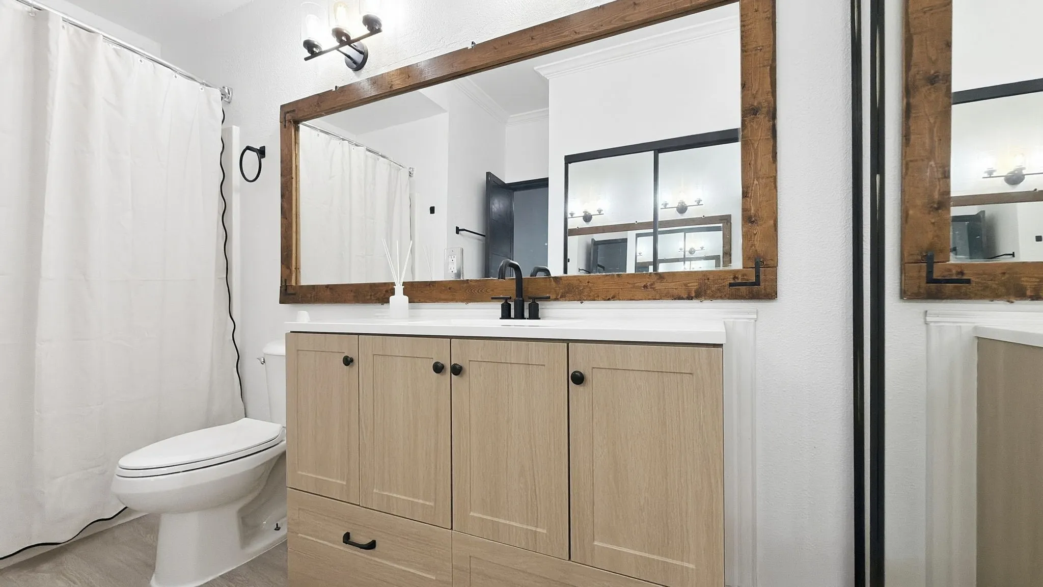 Wood-finish vanity with a light countertop, complemented by a large wood-framed mirror