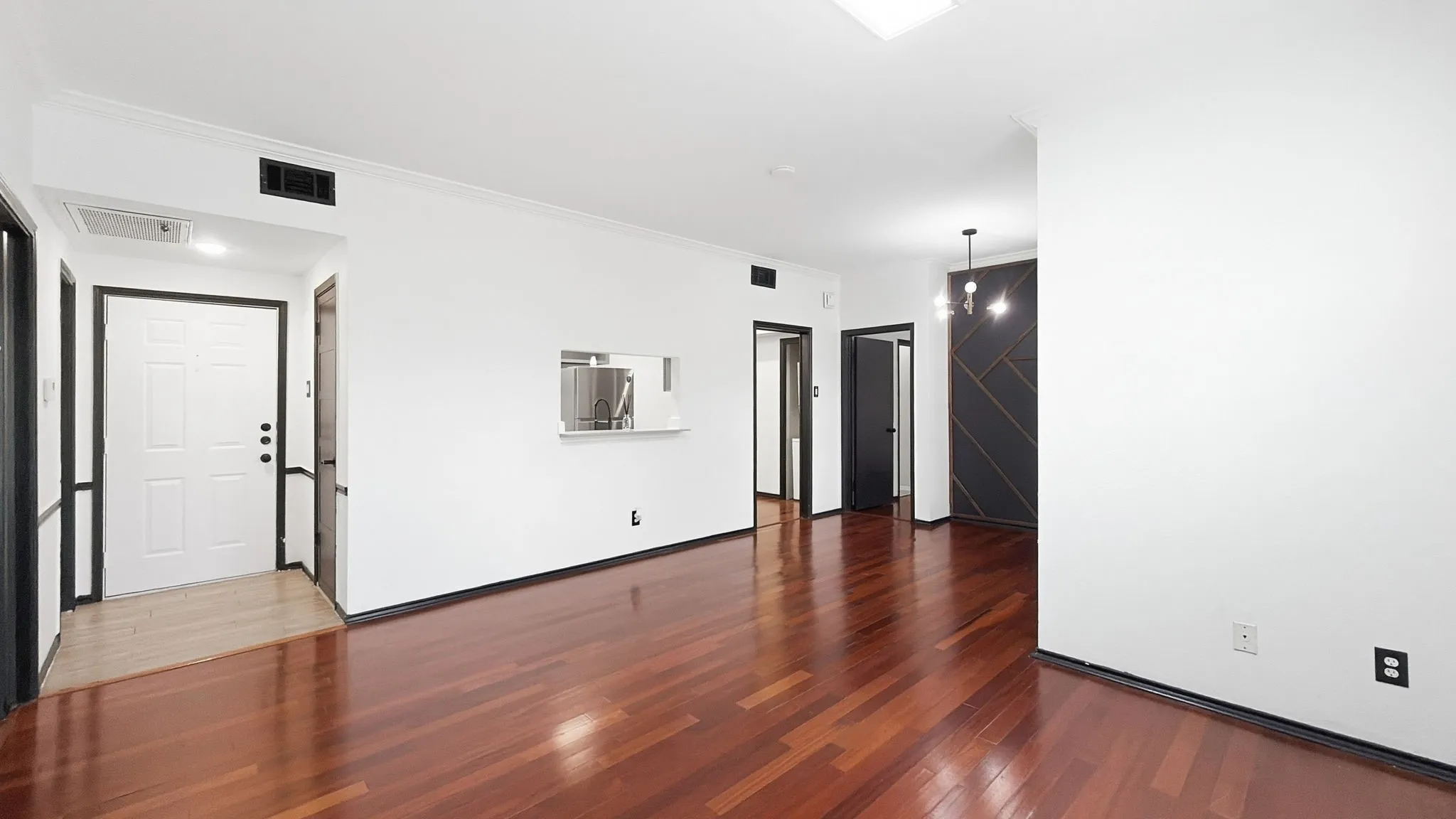 Hardwood flooring, crisp white walls, contemporary chandelier, recessed lighting, and a pass-through window
