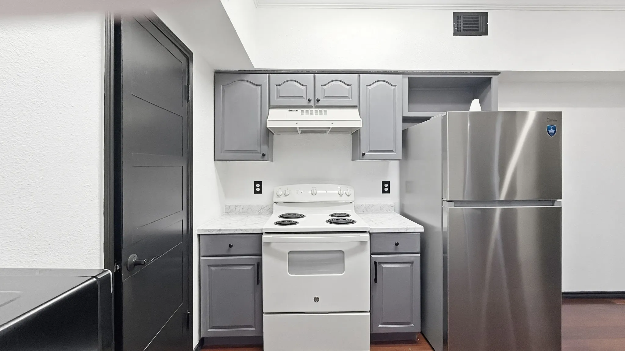 Kitchenette featuring gray cabinetry, stainless steel refrigerator, white electric range, and light-toned countertops