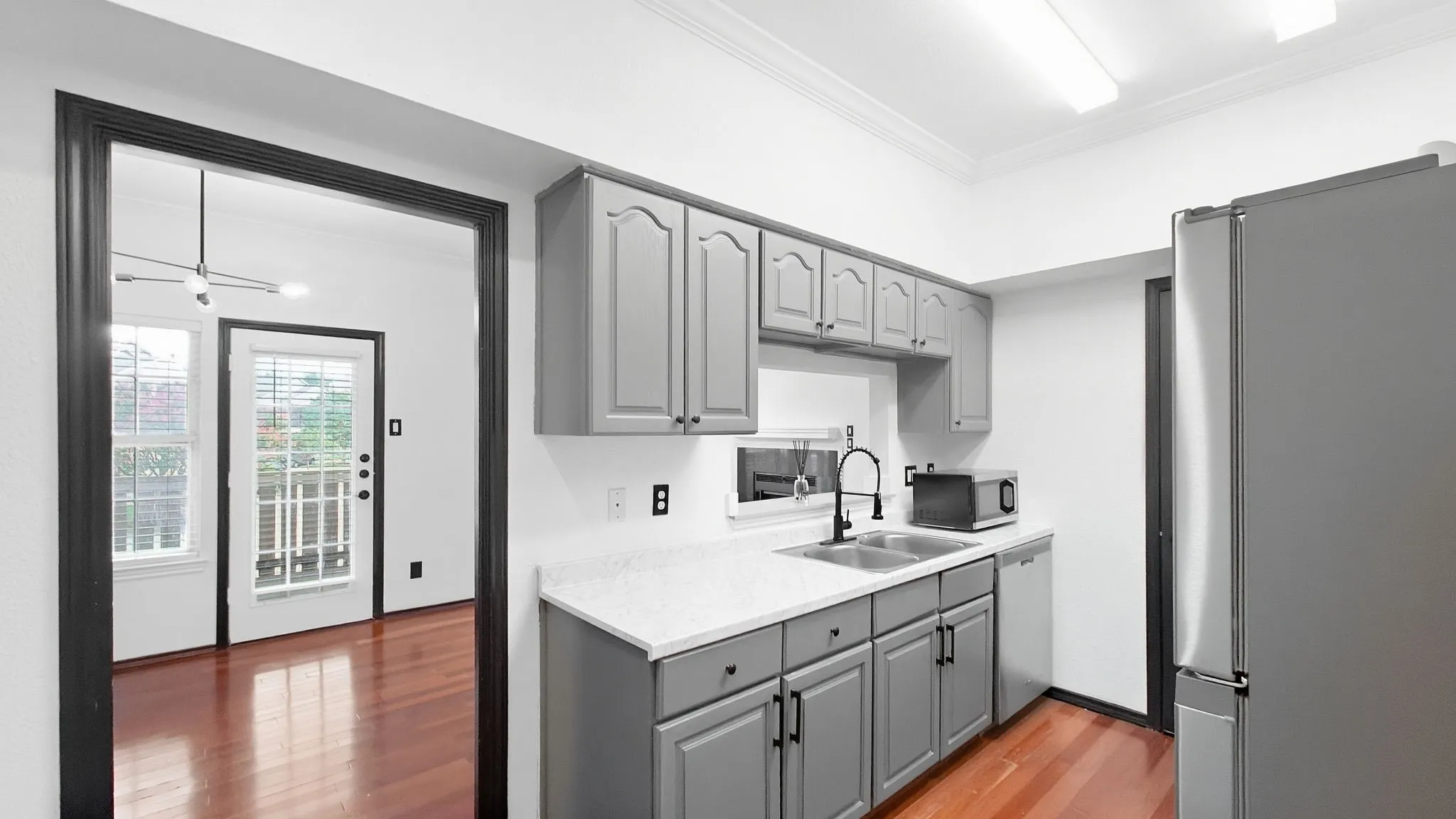 Kitchen with gray cabinetry, white countertops, stainless steel sink, and wood-finish flooring