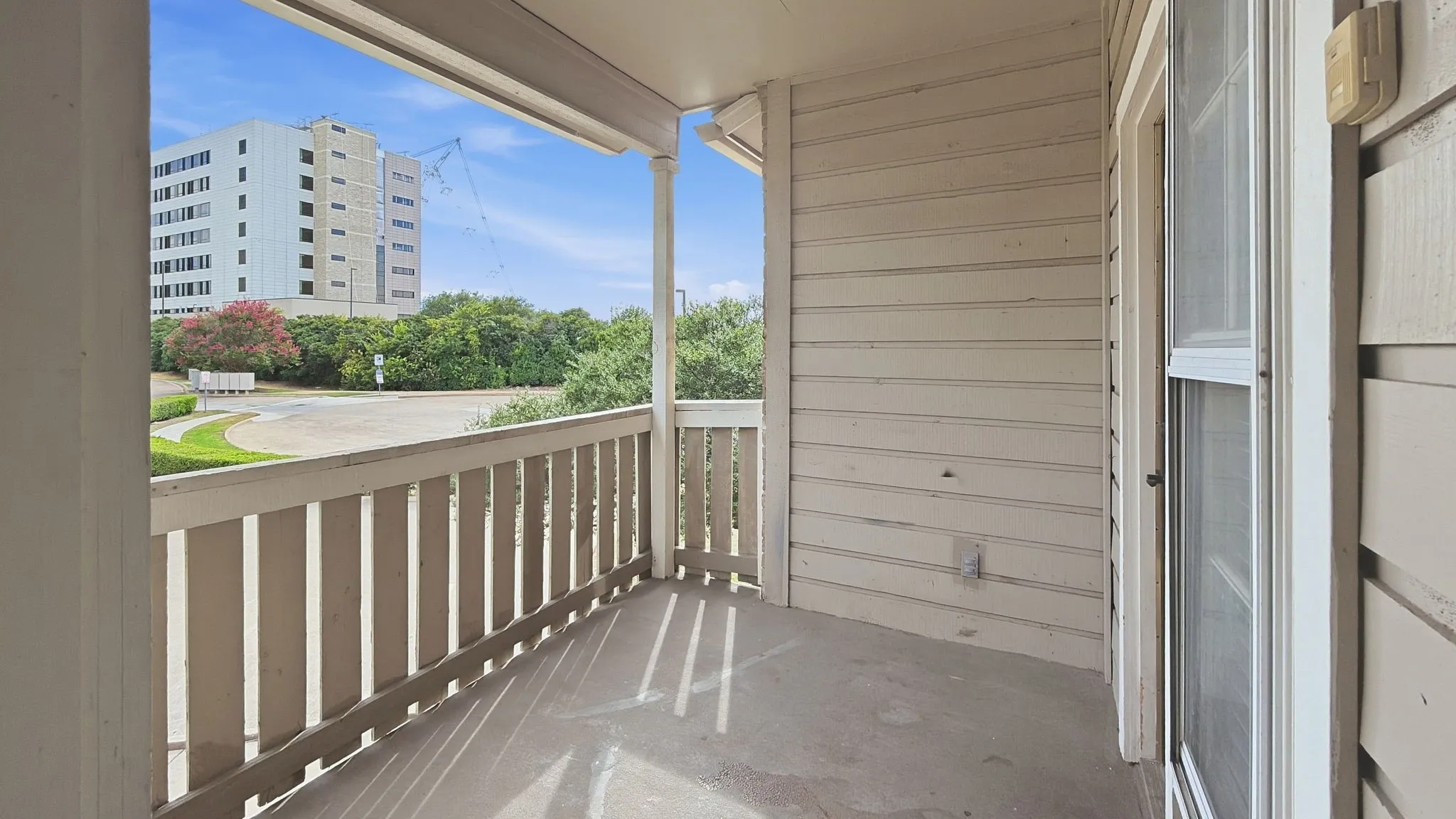 Private balcony with a concrete floor, wood railing, and an exterior sliding glass door
