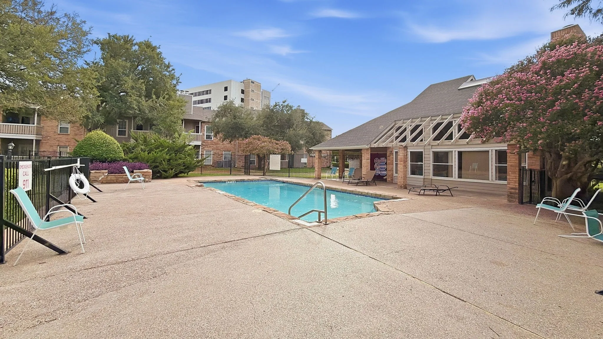 Outdoor swimming pool with integrated steps, surrounding concrete decking, and black metal fencing